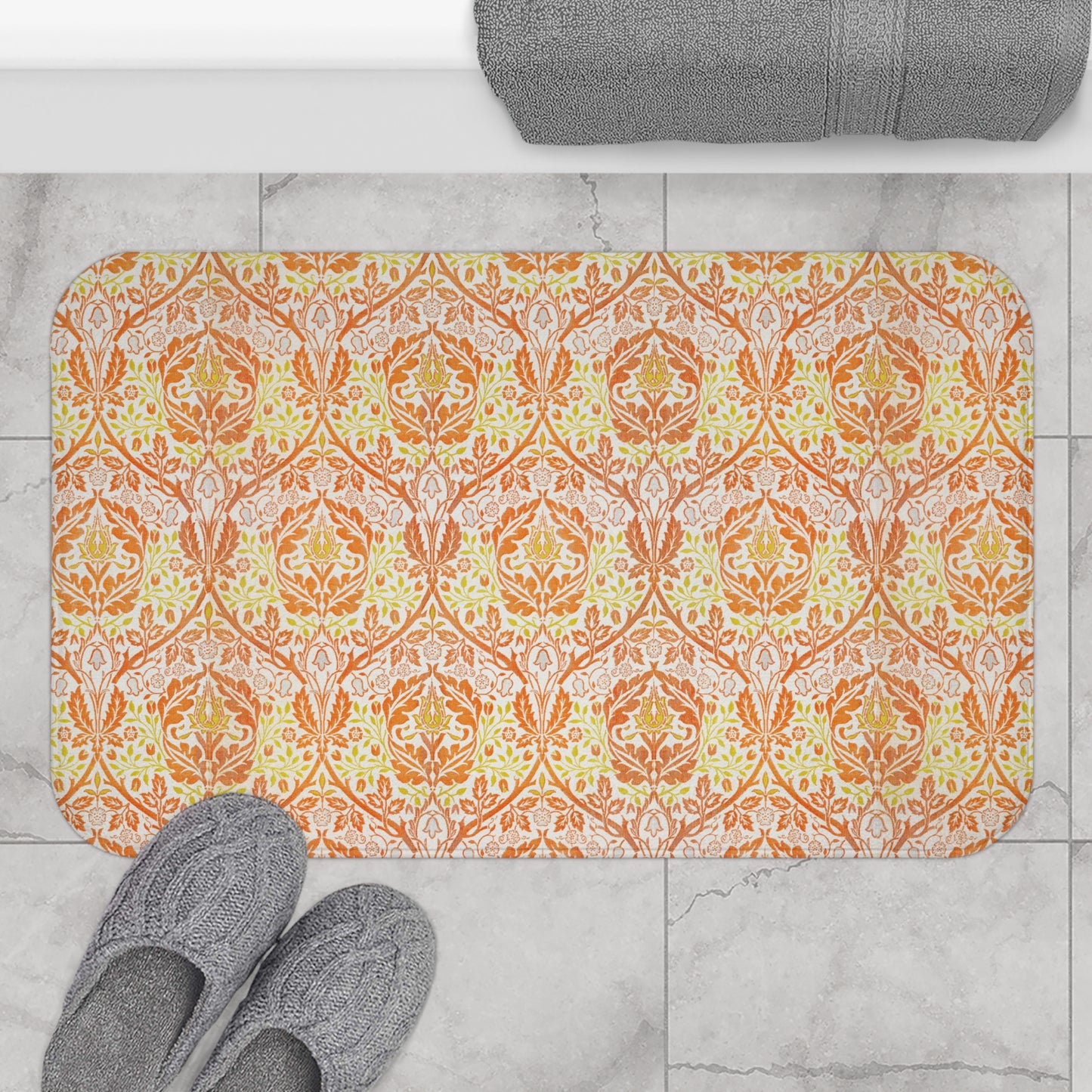 A rectangular microfibre bath mat with a floral pattern inspired by William Morris, in predominantly orange and yellow shades.