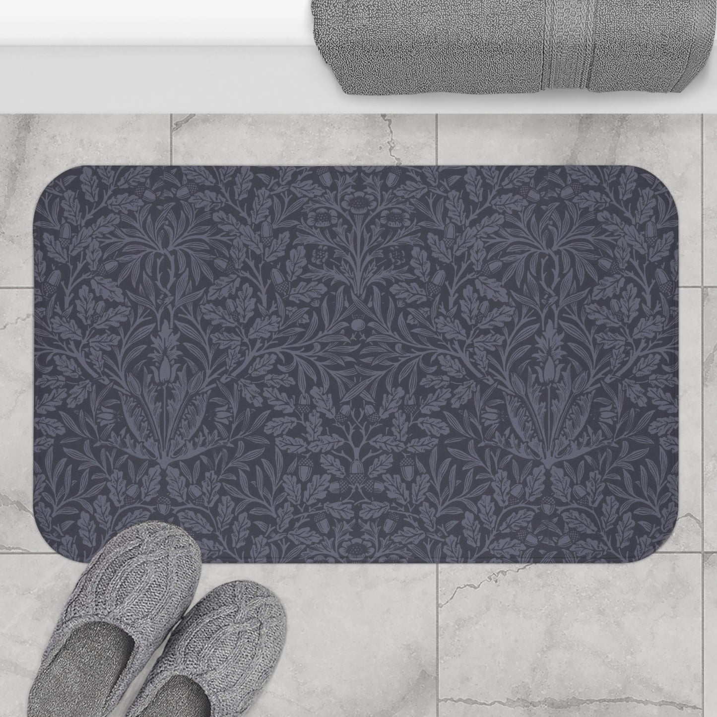 A rectangular microfibre bath mat with an all-over print of acorns and oak leaves in a smoky blue colour.