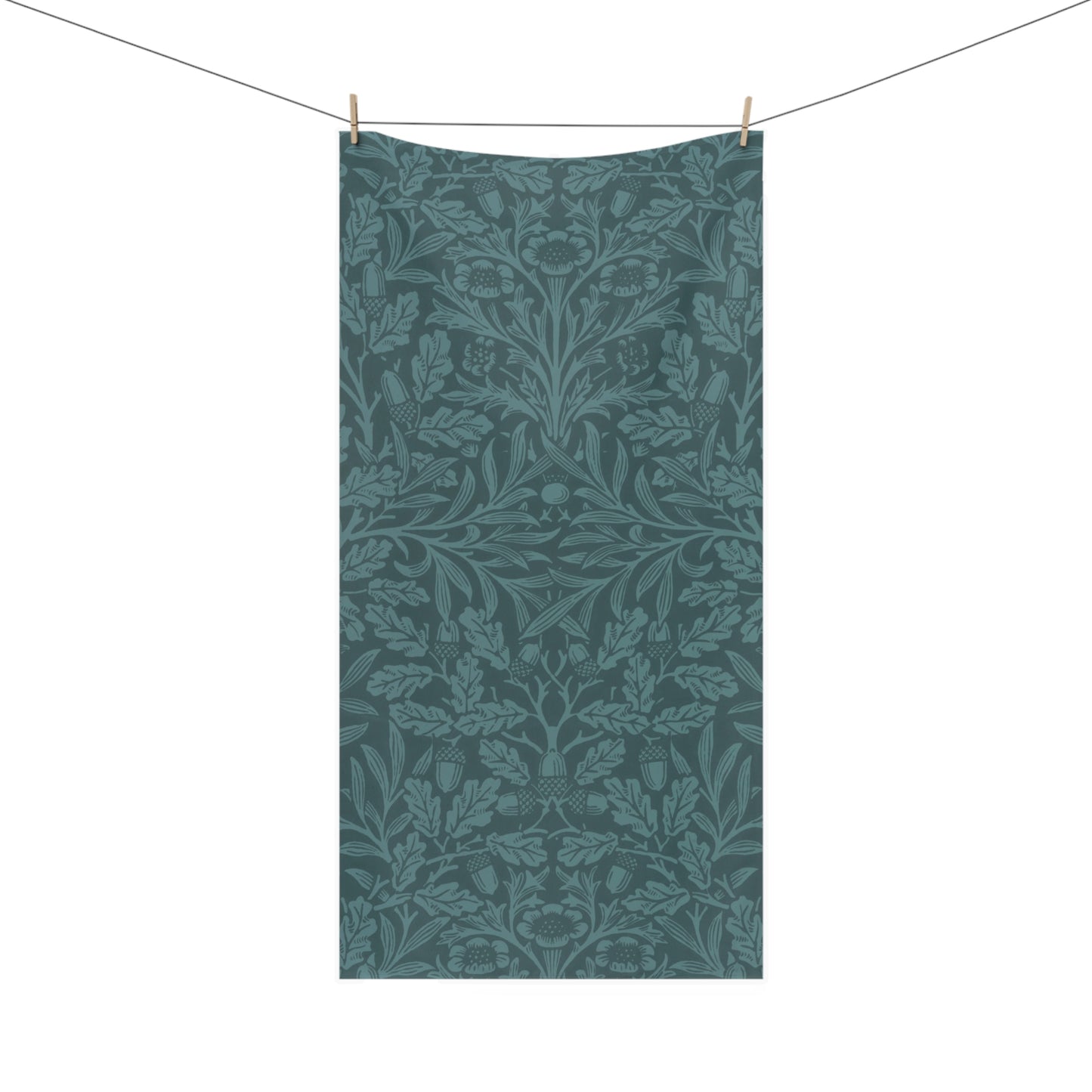 A rectangular bath towel hanging from a clothesline with two wooden clips, featuring an all-over botanical and floral pattern in muted teal and blue-green tones on a white background.
