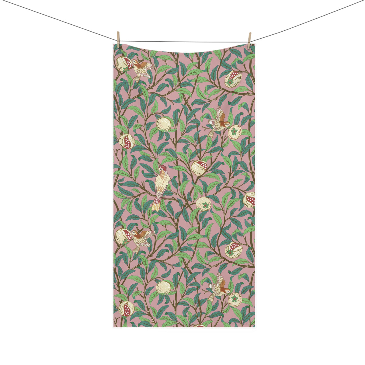 A rectangular bath towel from a clothesline with two wooden clips, featuring an all-over botanical and bird pattern on a dusty pink background with green leaves, brown branches, and small birds.