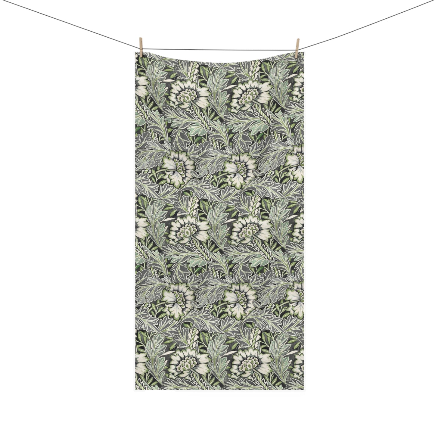 A rectangular fabric towel with a dense botanical pattern of white flowers and green leaves on a dark gray background, hanging from two wooden clothespins on a thin wire against a plain white background.