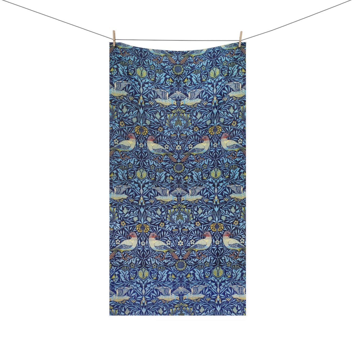 A rectangular towel hanging from a clothesline with two wooden clips, featuring a dense blue floral and bird pattern with pink, white, and yellow details on a white background.