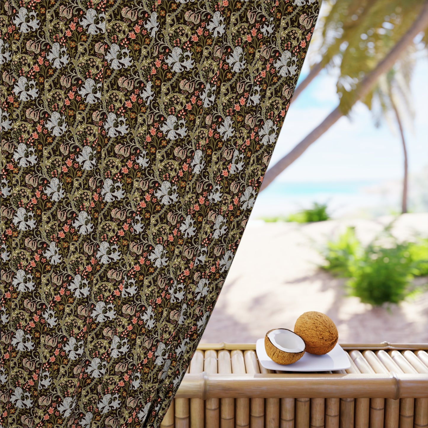 Decorative curtain with floral pattern in front of a beach view with coconuts on a table.