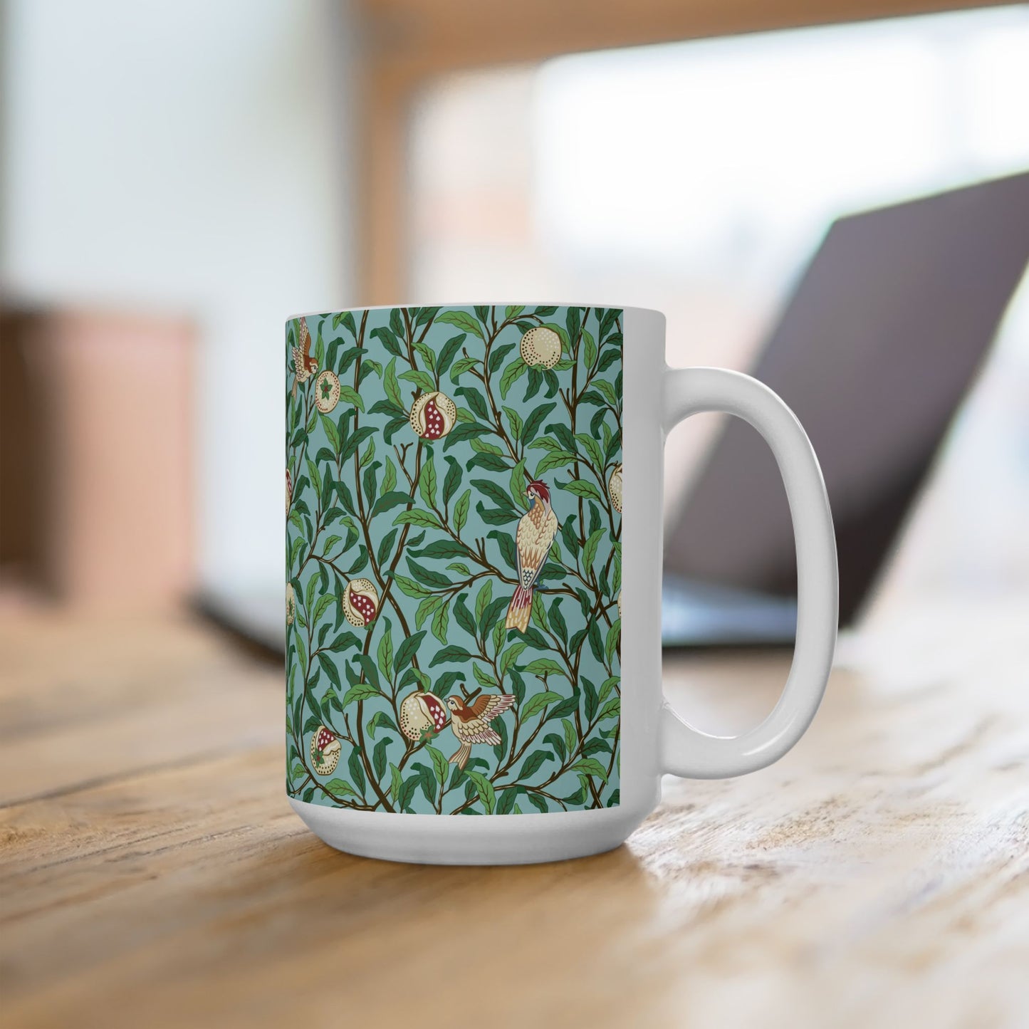 A ceramic mug with a blue background featuring a floral pattern of birds and pomegranates.