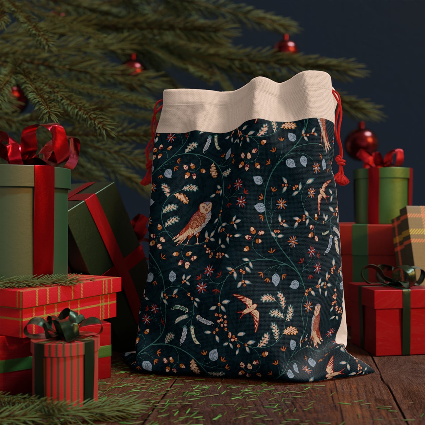 Decorative Christmas sack with nature-themed design in front of gift boxes and a tree.