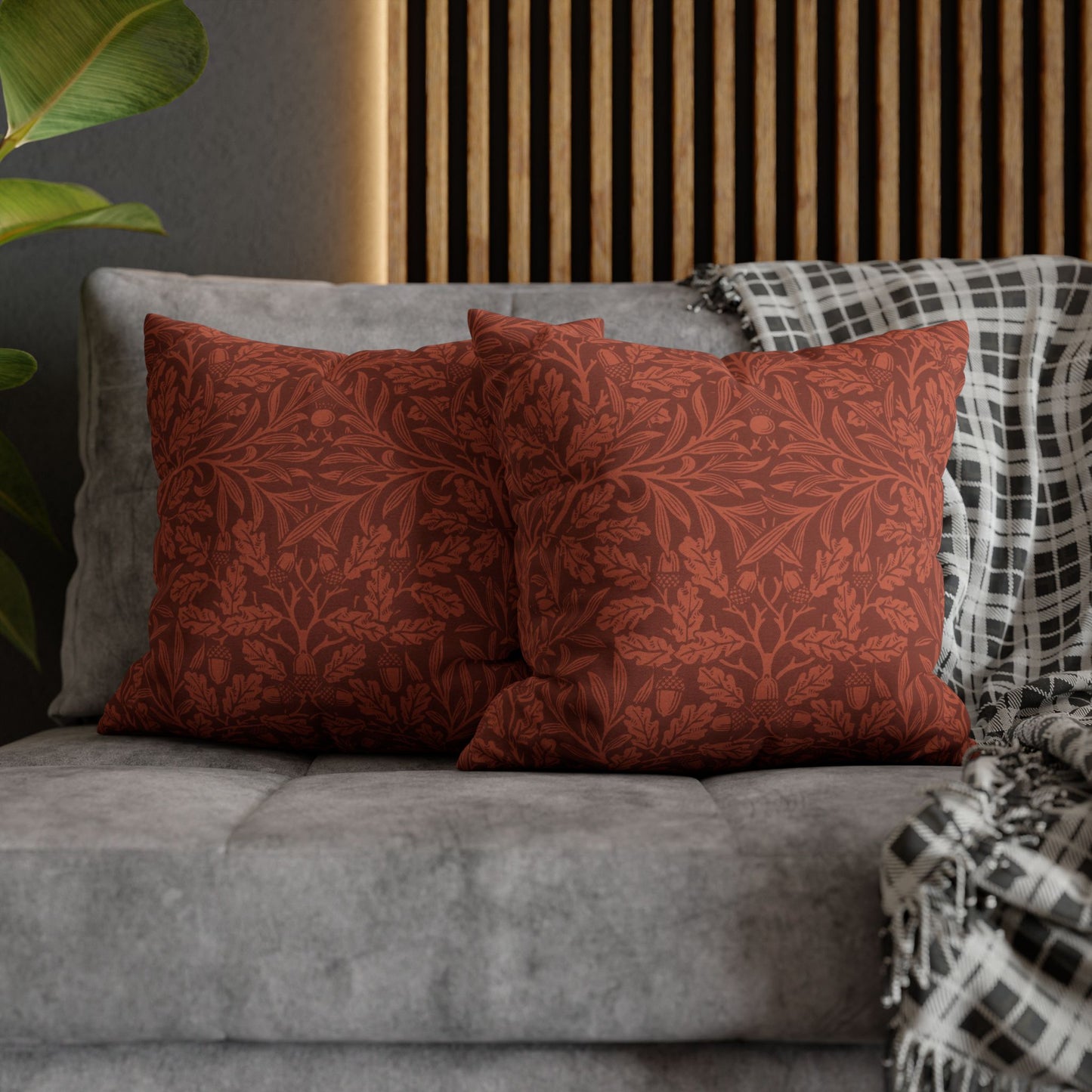 Red patterned pillows on a gray sofa with a wooden headboard in the background