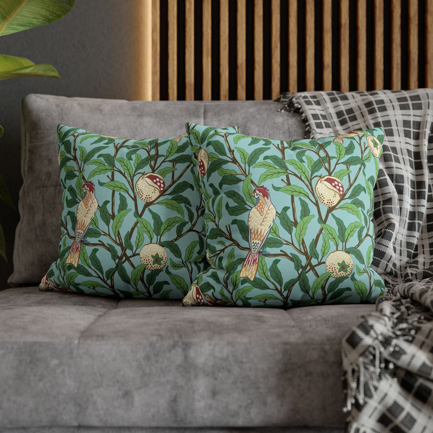 Two decorative pillows with bird and leaf pattern on a gray sofa.