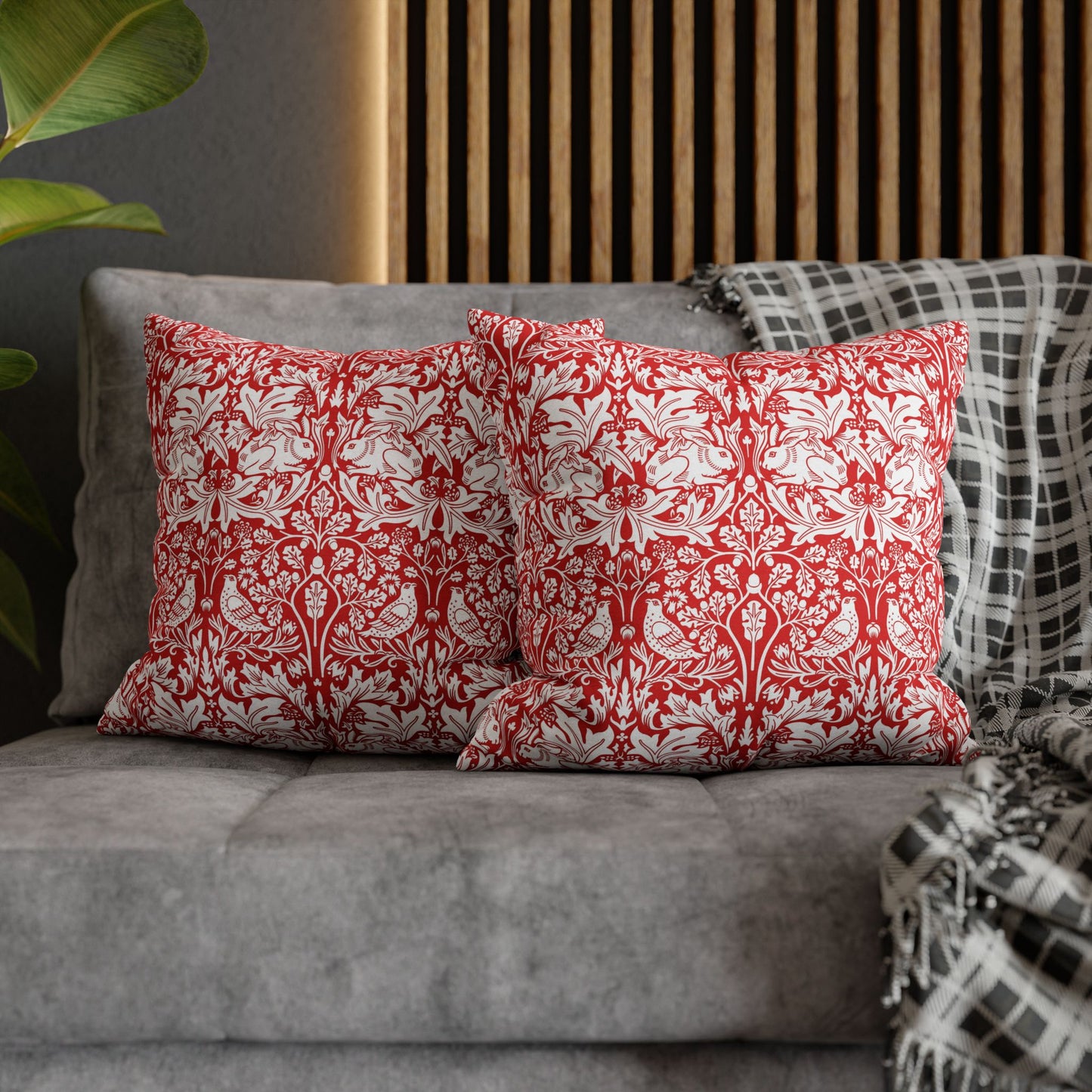 Red and white patterned pillows on a gray sofa with a wooden headboard in the background.