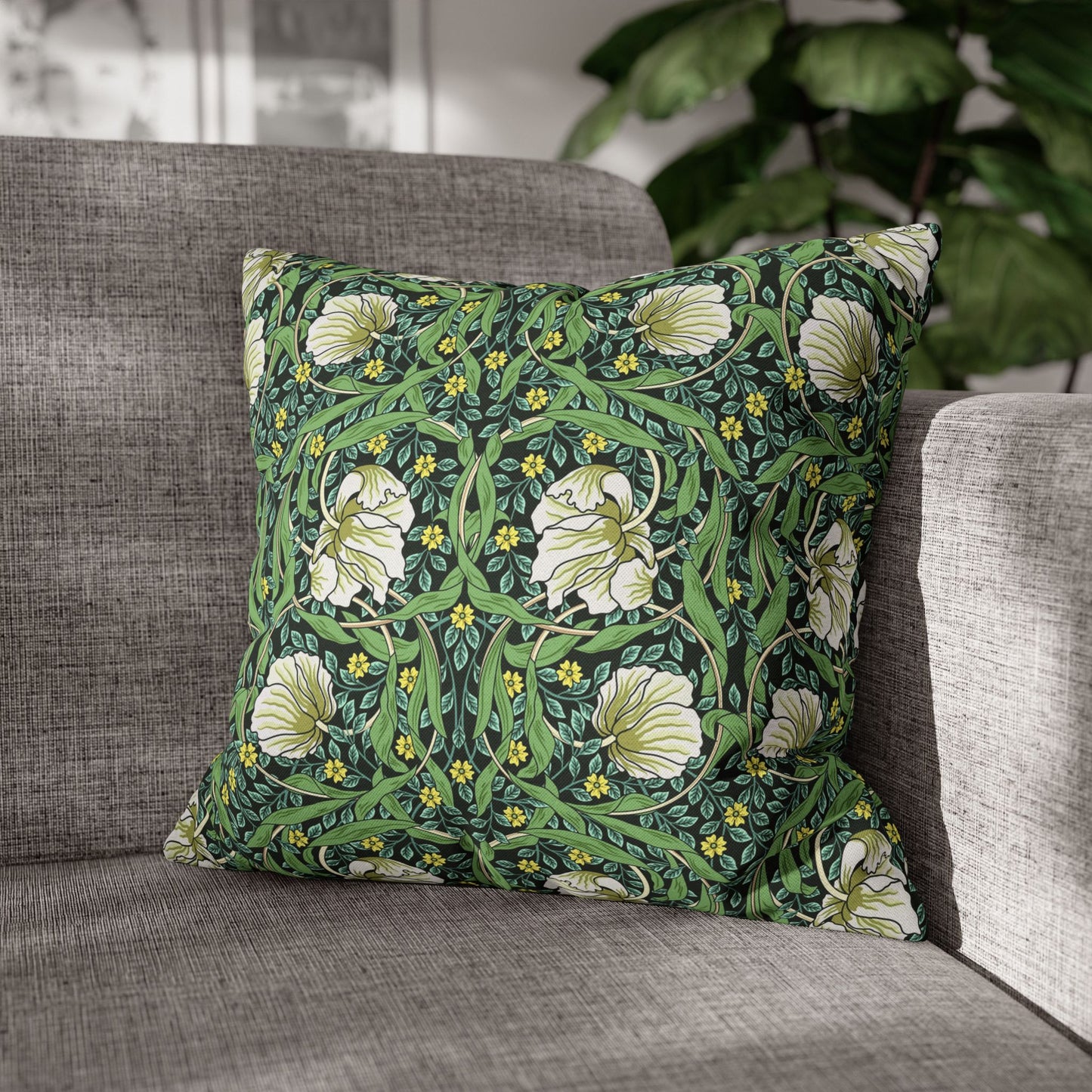 Floral patterned pillow on a gray sofa with a blurred plant in the background