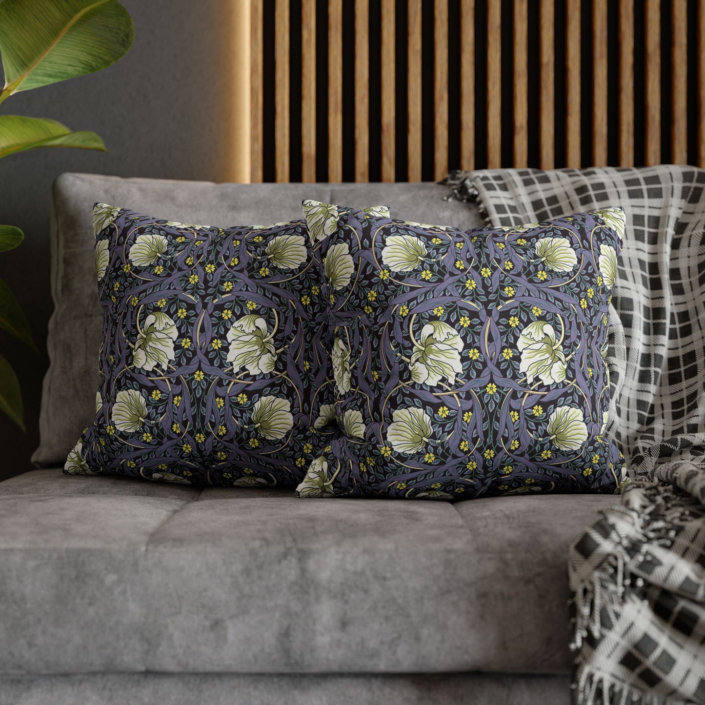 Decorative pillows with floral pattern on a gray sofa against a wooden panel wall.