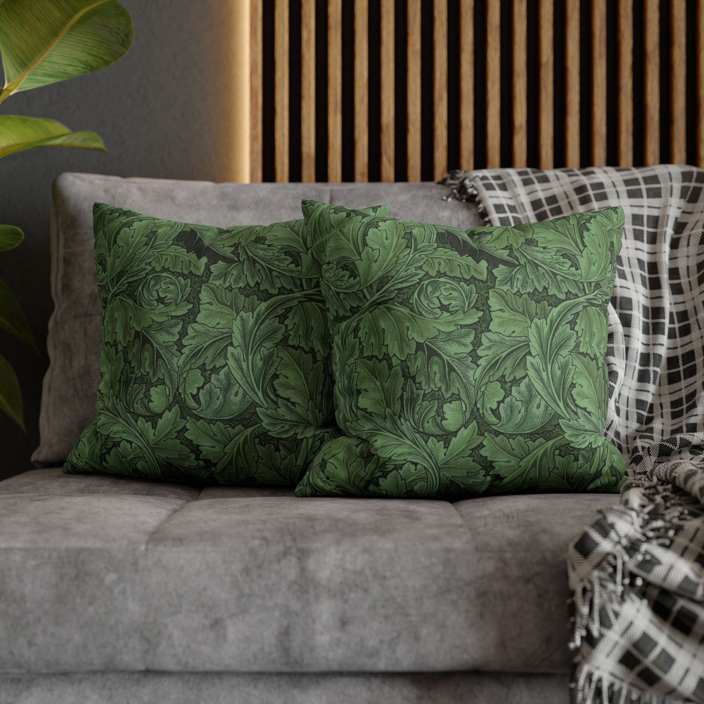 Green patterned pillows on a gray sofa with a wooden headboard in the background