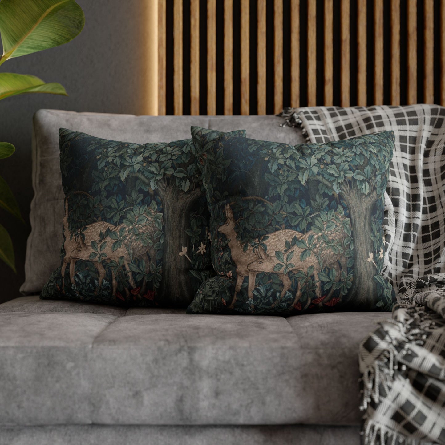 Decorative pillows with deer design on a gray sofa against a wooden panel wall.
