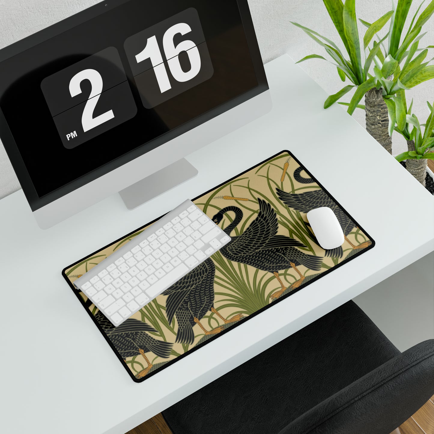 A large desk mat with a pattern of black swans, placed on a desk under a keyboard and a mouse, with a monitor mounted on the desk.