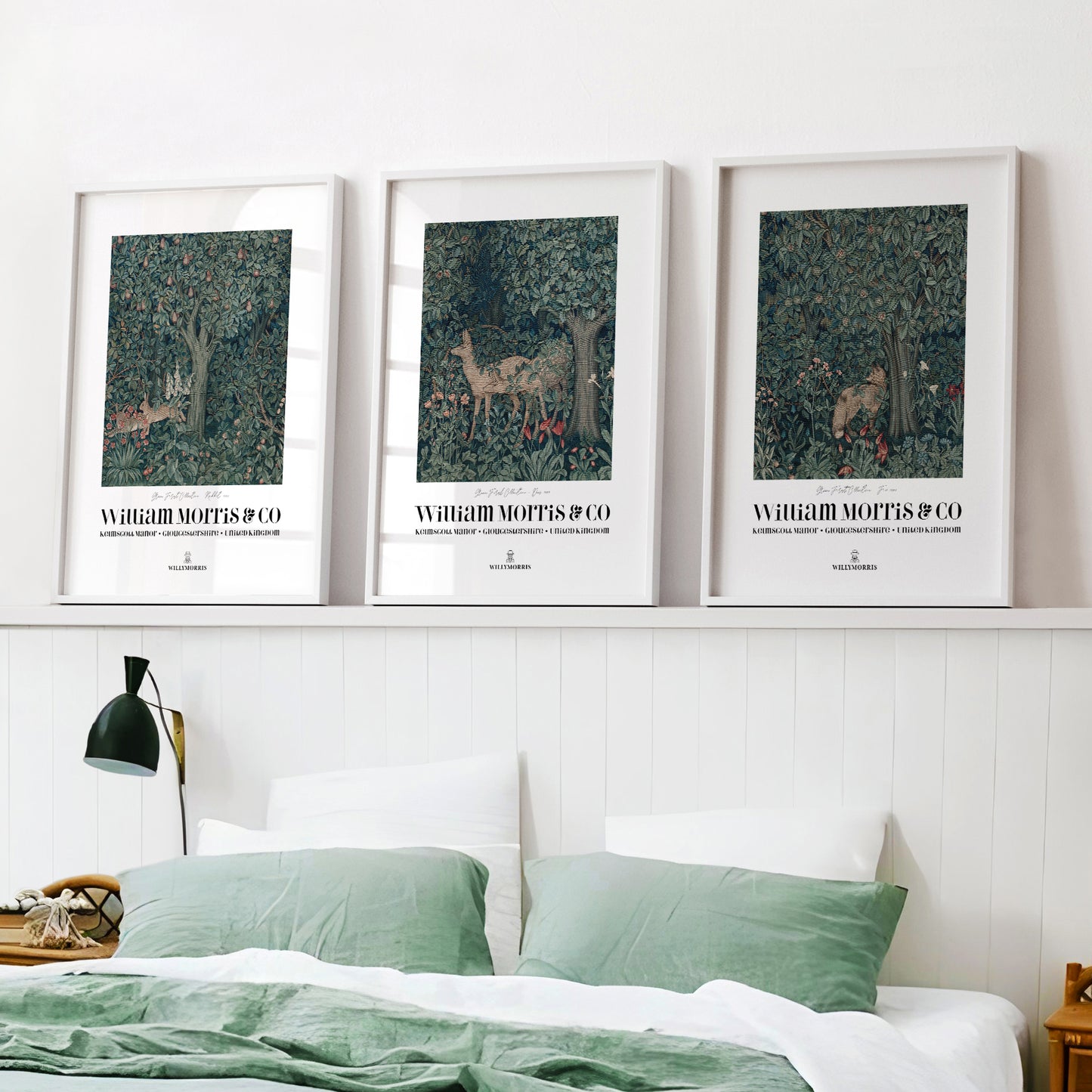 Three framed artworks above a bed with green bedding on a white wall.