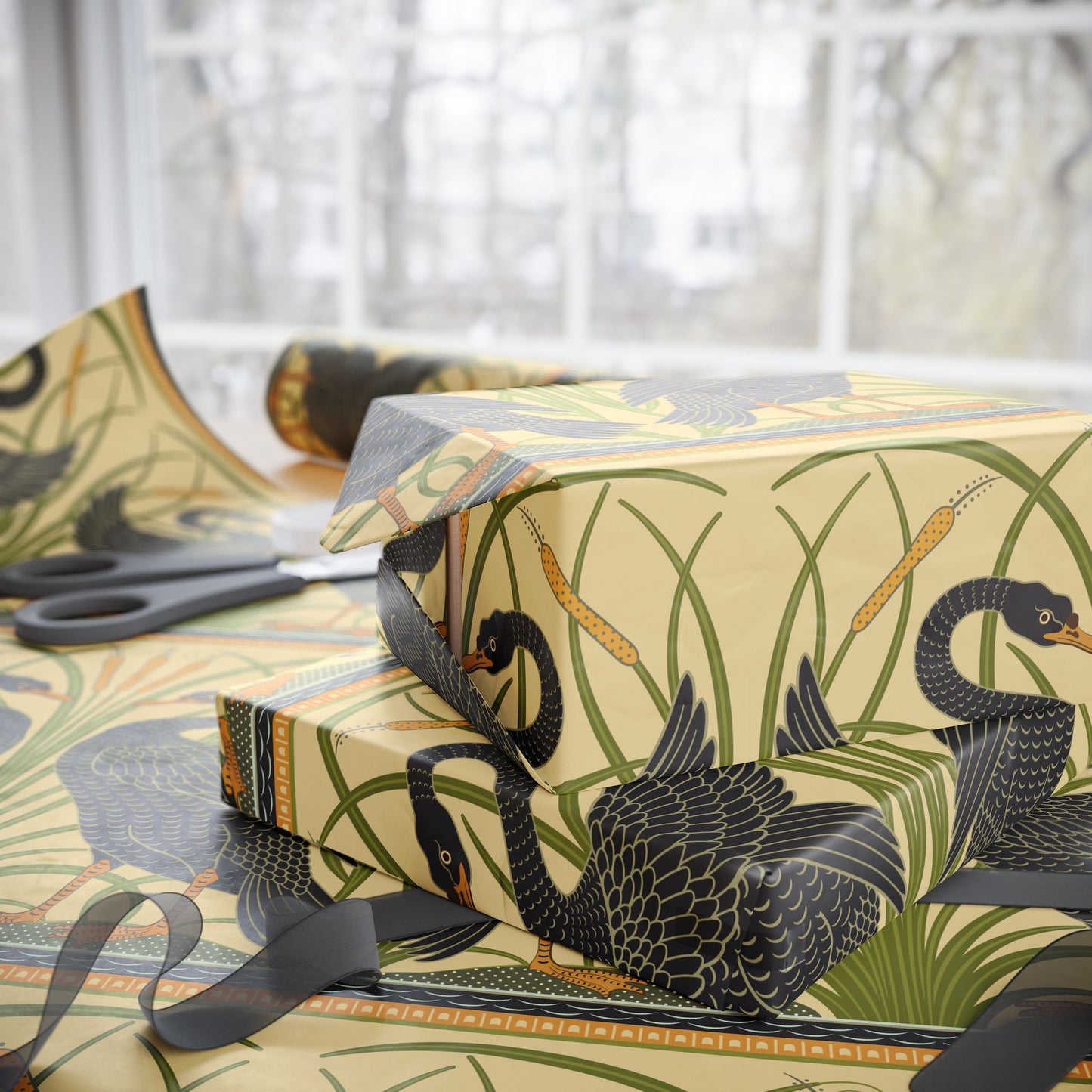 Gift box with black swan design on patterned paper, scissors visible.