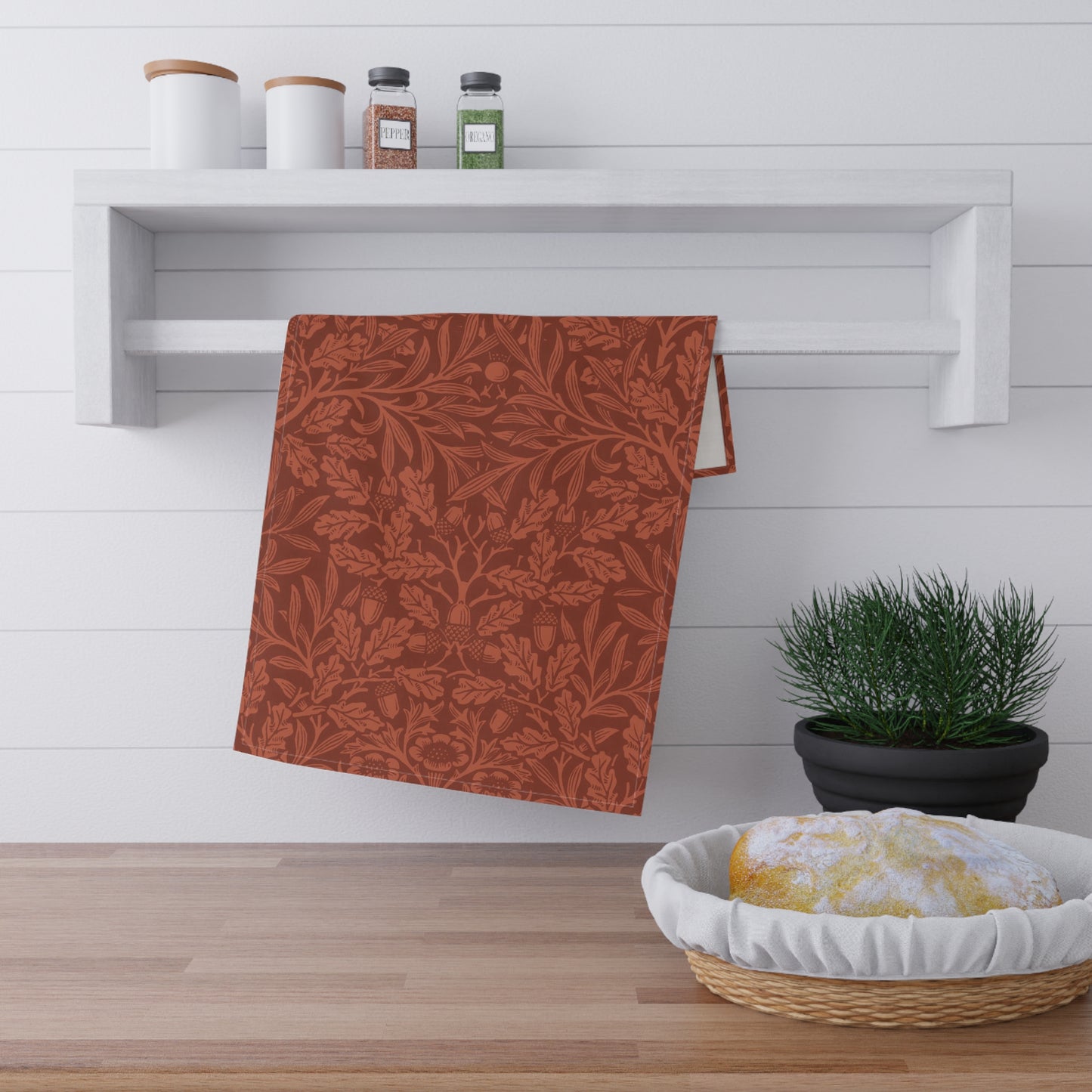 A kitchen tea towel with a floral and leaf William Morris & Co pattern, primarily in a brown and colour.