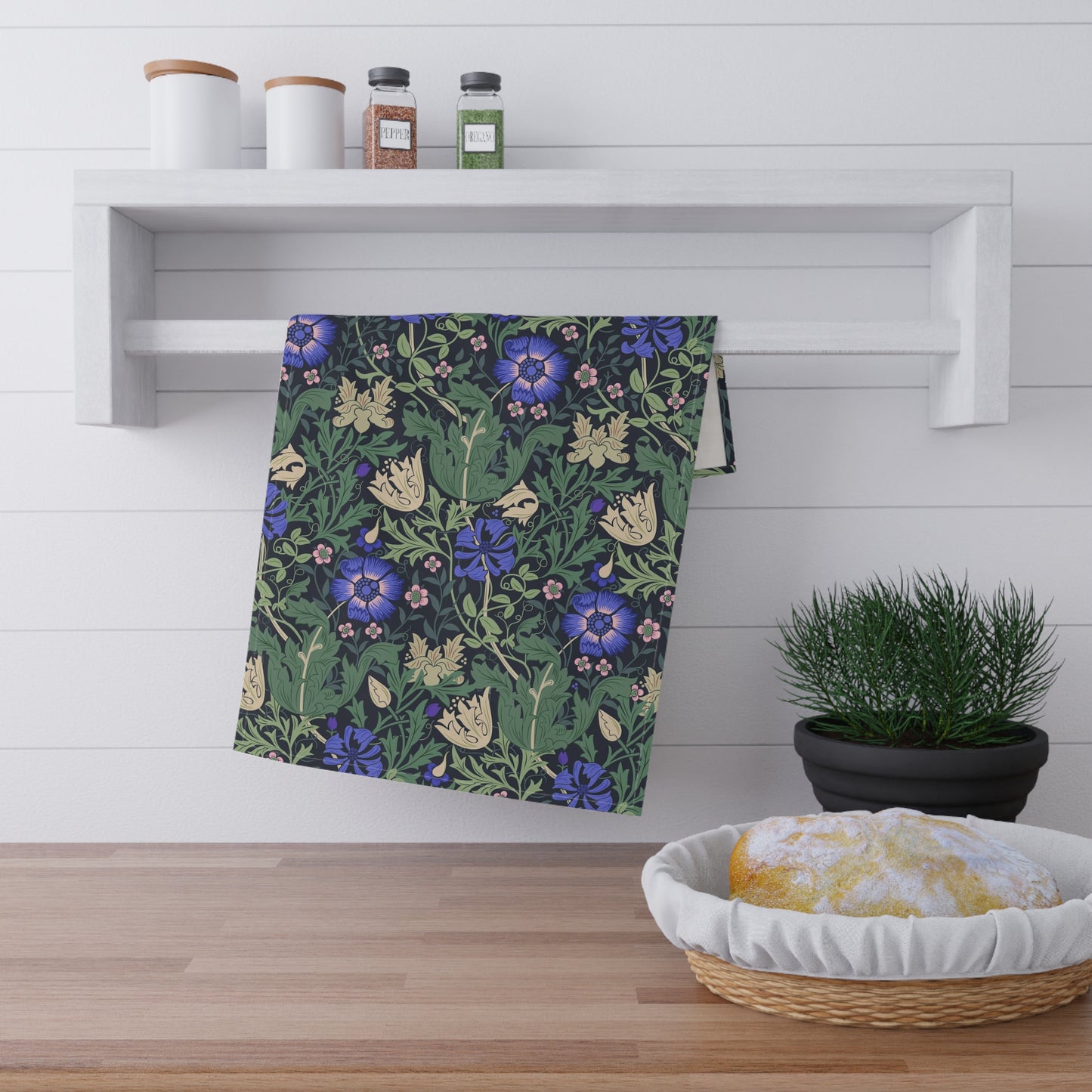 A kitchen tea towel with a floral William Morris & Co pattern featuring blue and green colours on a beige background.