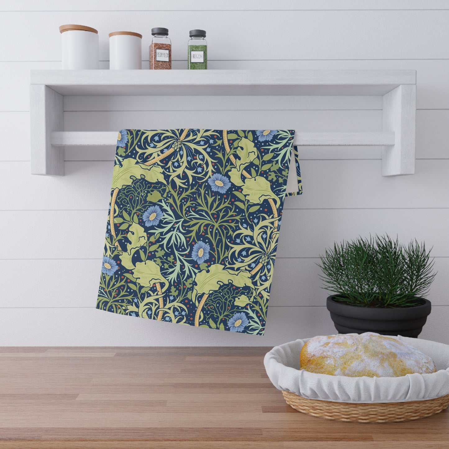 A rectangular kitchen tea towel featuring a floral Arts & Crafts pattern from William Morris & Co with blue flowers and green leaves on a cream background.