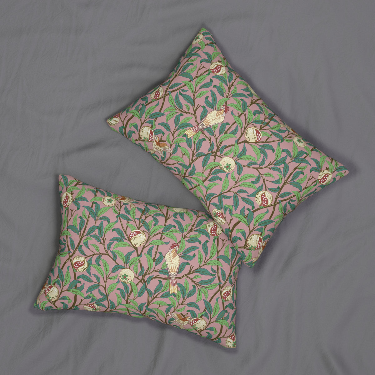 Two square decorative throw pillows with a pink, green, and brown botanical bird pattern, displayed on a gray fabric background.