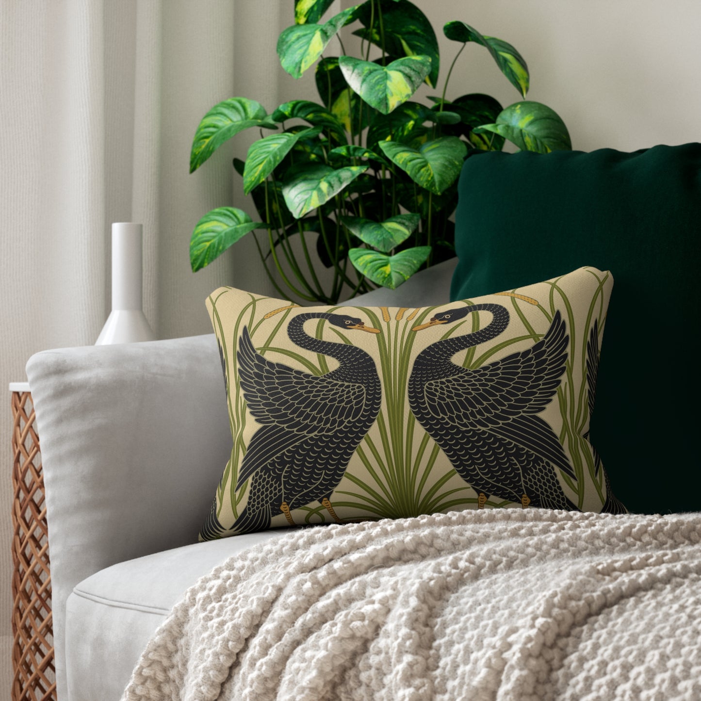 A rectangular lumbar cushion with a black and green William Morris & Co pattern featuring stylised swan figures.