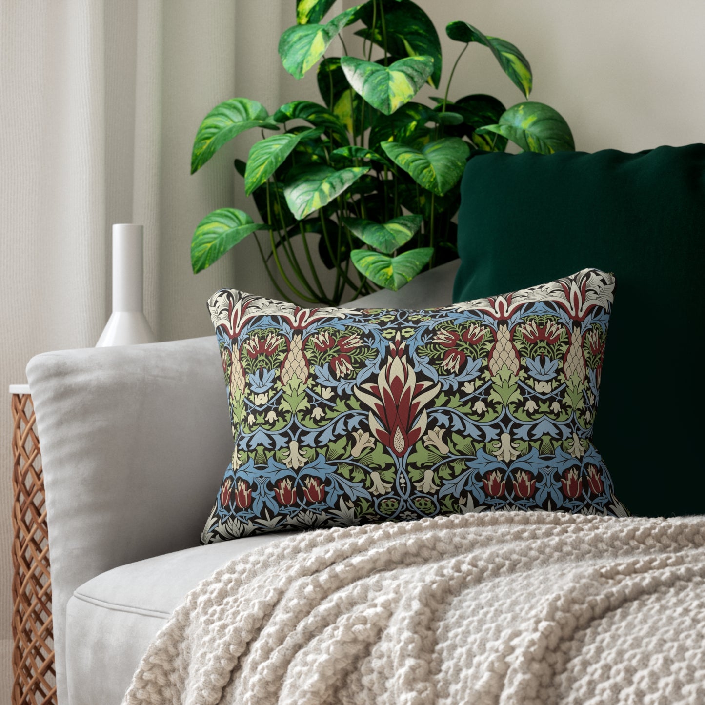 A rectangular lumbar cushion with a William Morris & Co floral and geometric pattern in multiple colours, including blue, beige, and green, with a concealed beige zipper.
