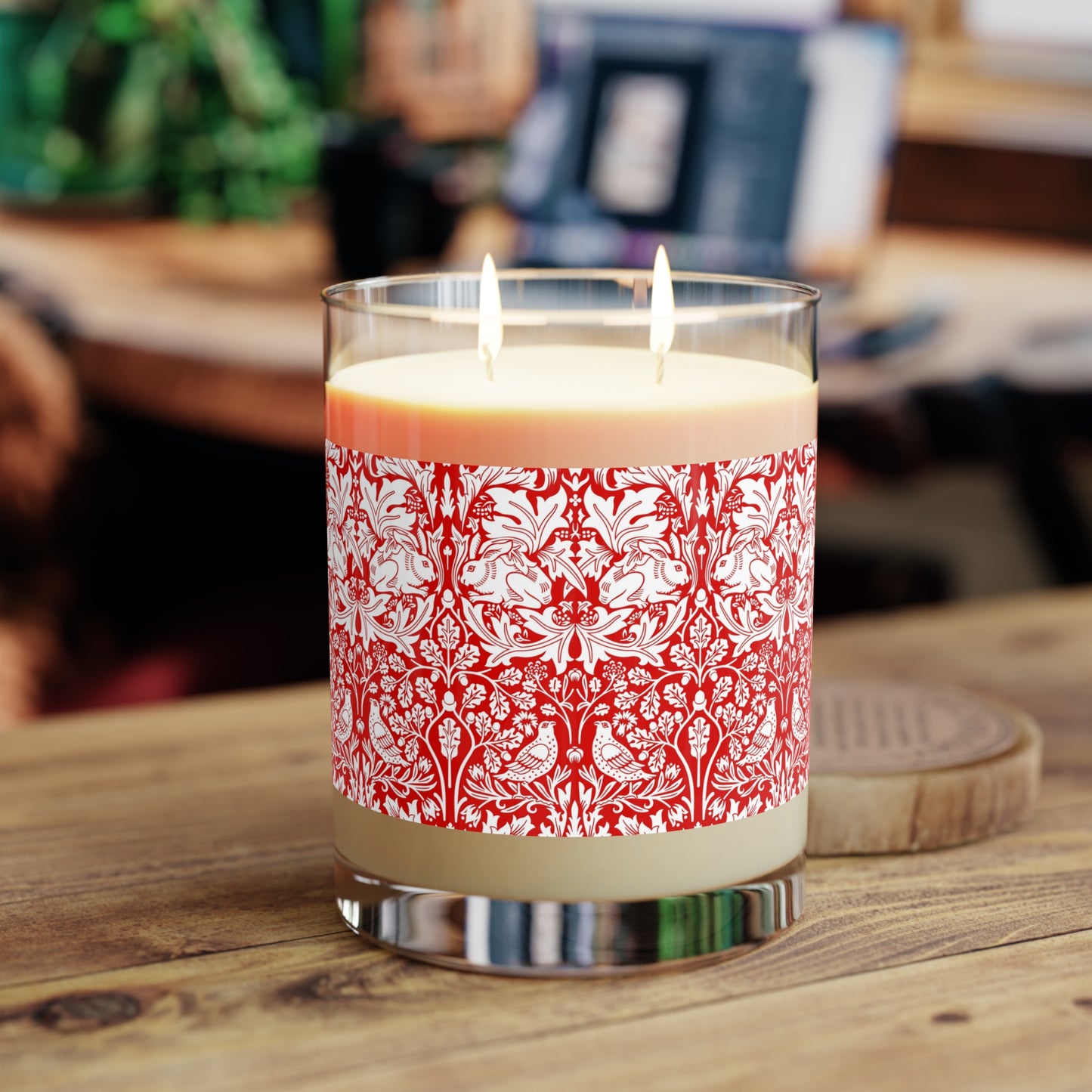 Candle with red floral pattern and wooden lid on a white background