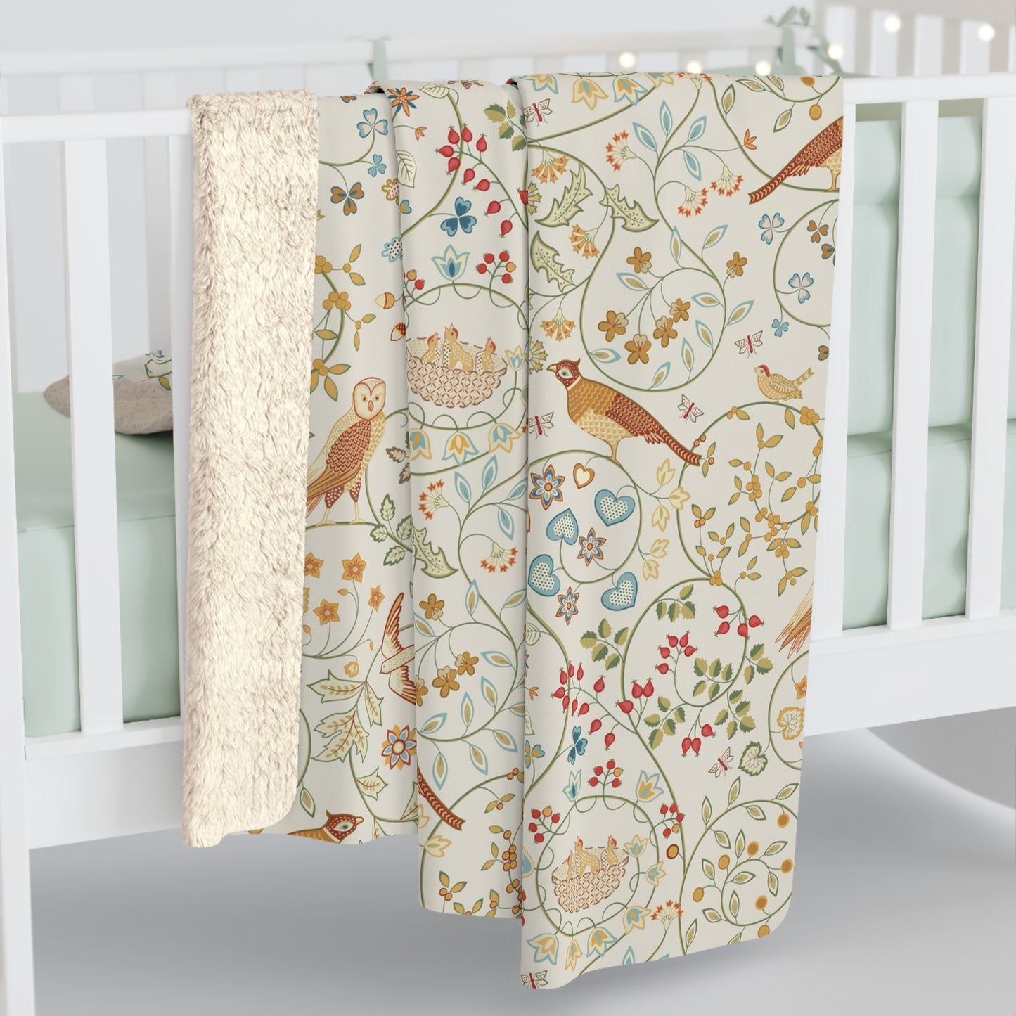 Floral and nature-themed baby blanket with birds and flowers on a white crib.