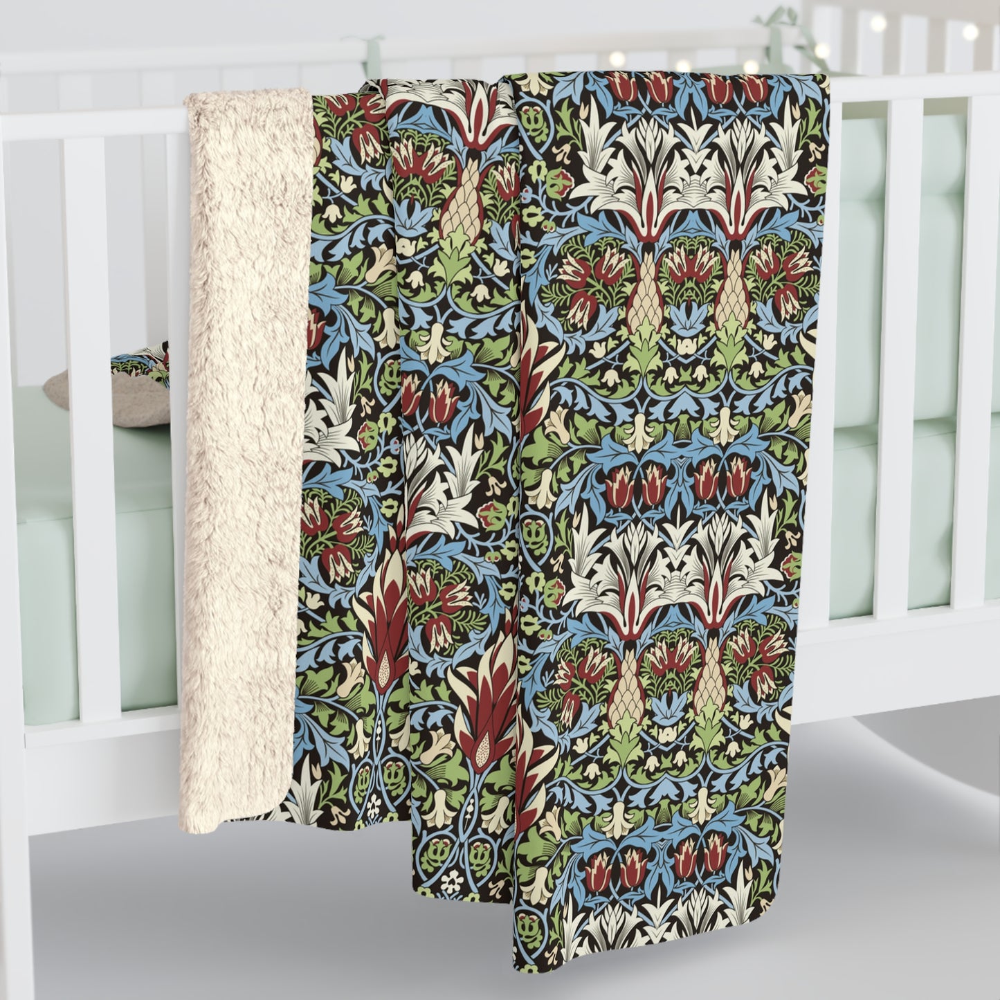 Decorative blanket with a colourful pattern draped over a white crib from William Morris