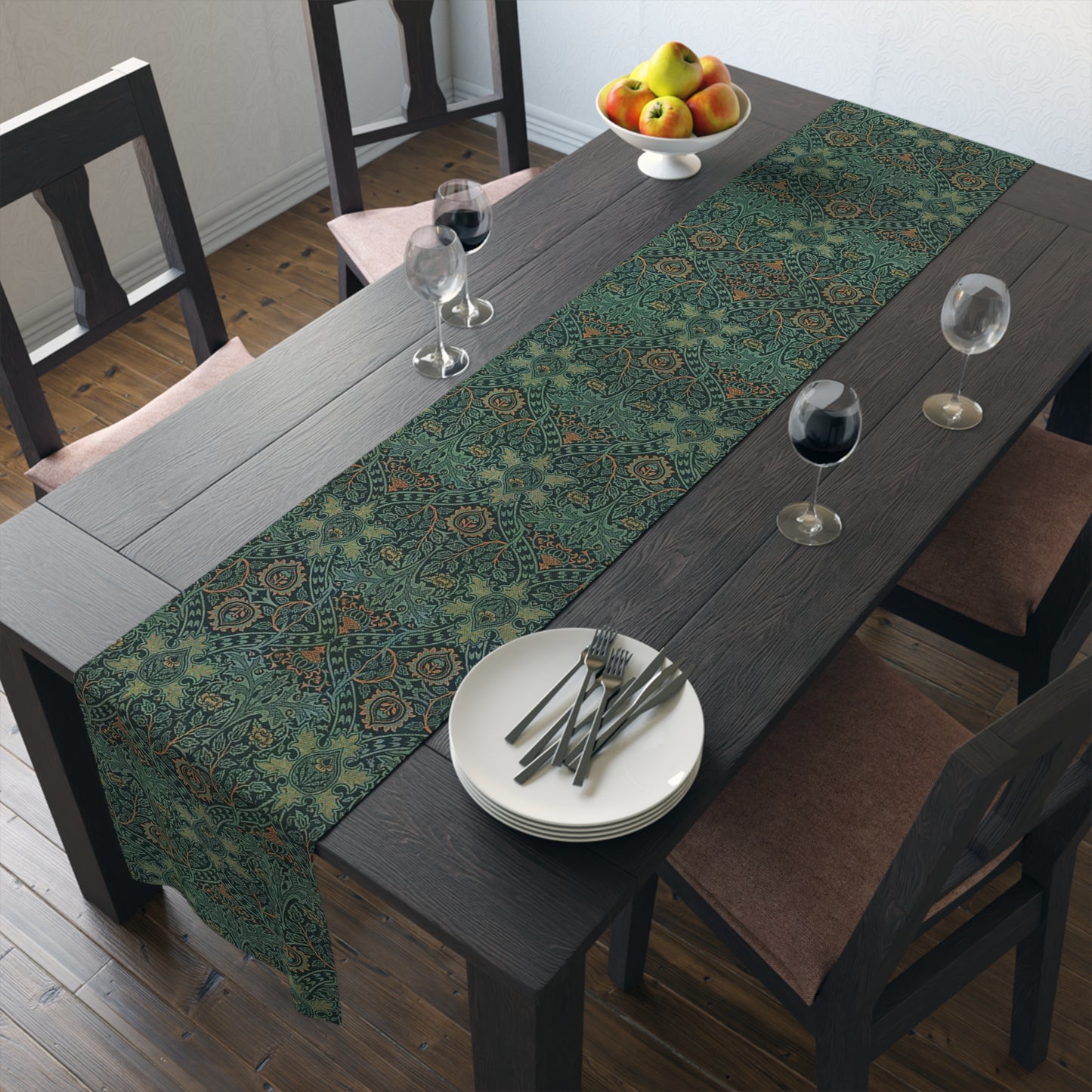 A green table runner with a floral pattern inspired by William Morris, displayed on a dining table with dishes and cutlery.
