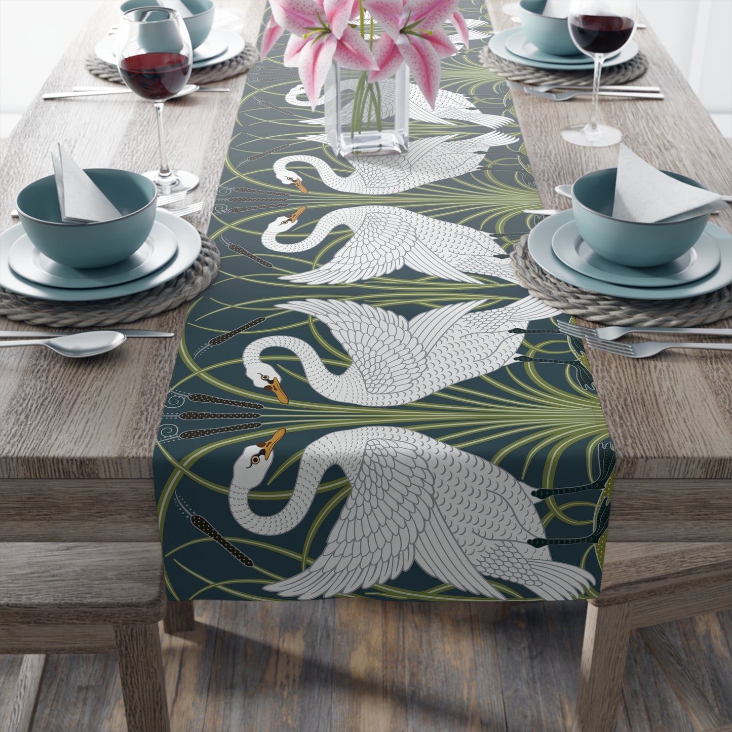 Table setting with a decorative table runner featuring swan designs on a wooden table.