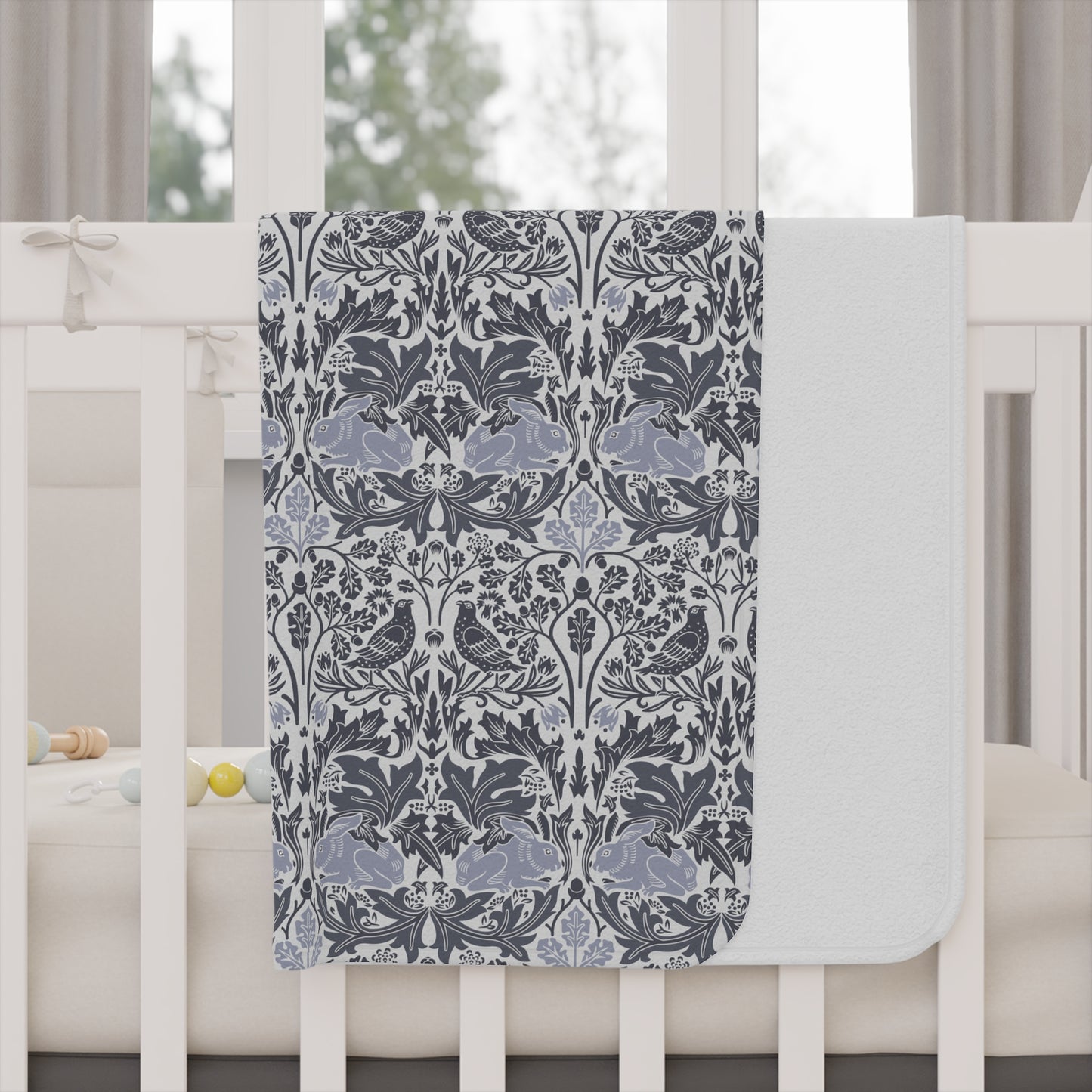Decorative floral-patterned blanket draped over a crib in a nursery setting.