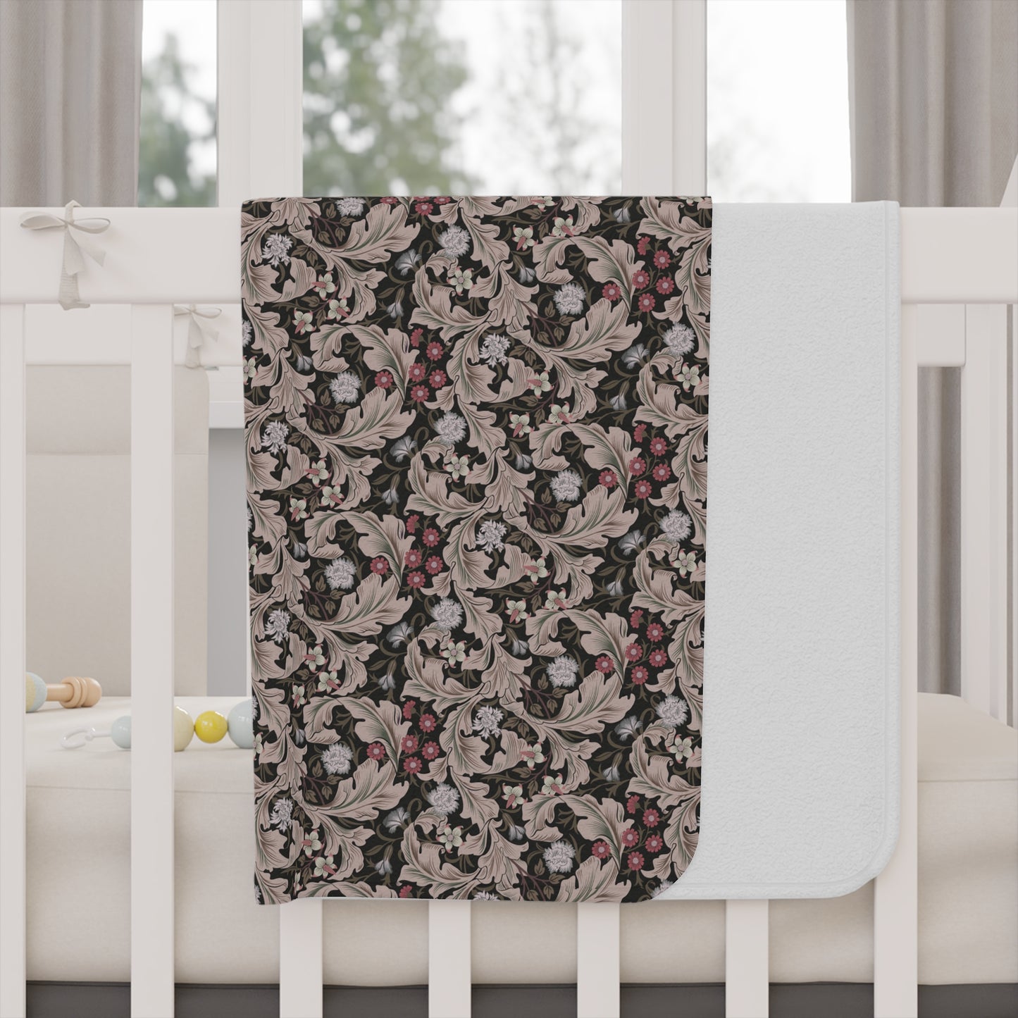 Floral patterned blanket draped over a crib in a nursery setting