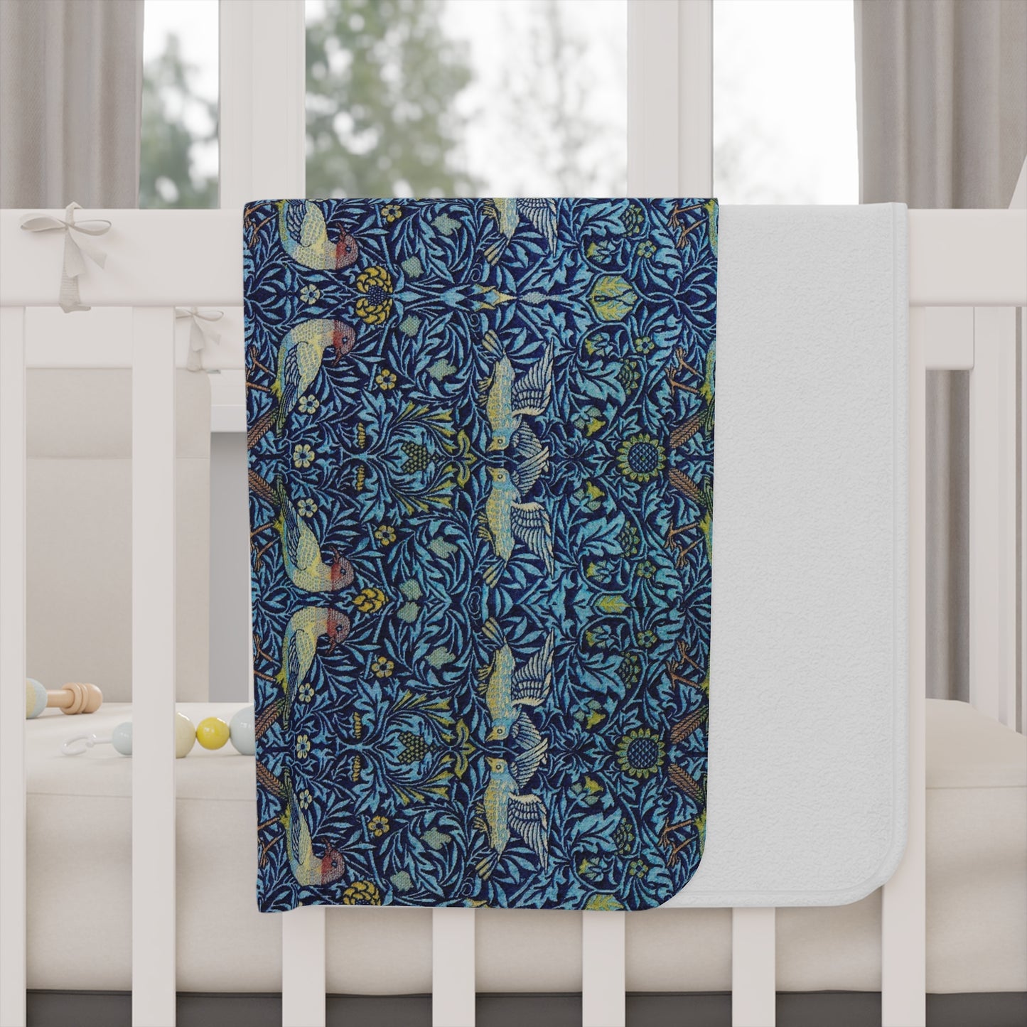 Decorative blanket with a floral and bird pattern draped over a crib.