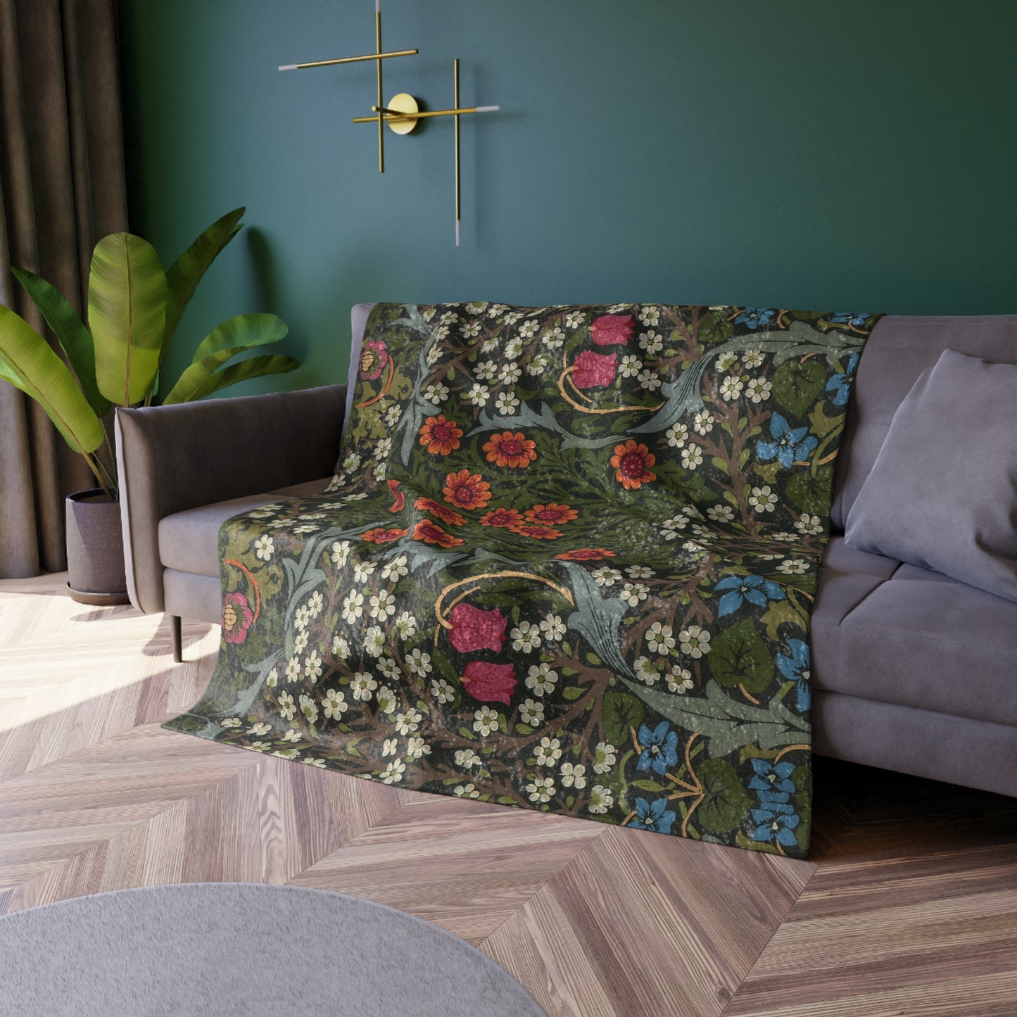 Floral-patterned throw blanket on a sofa against a green wall with decorative elements.
