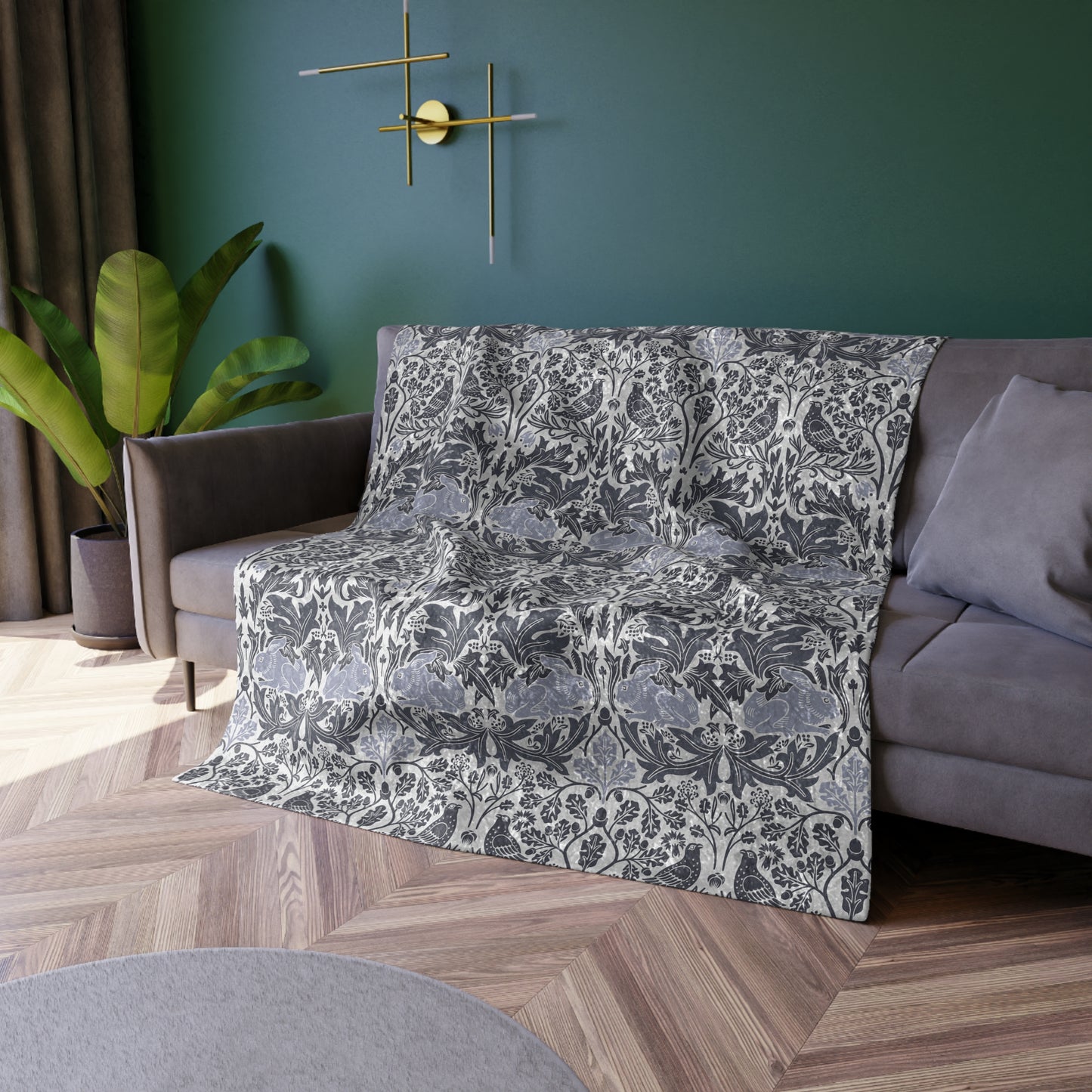 Floral-patterned throw blanket draped over a sofa in a living room with green walls and a plant.