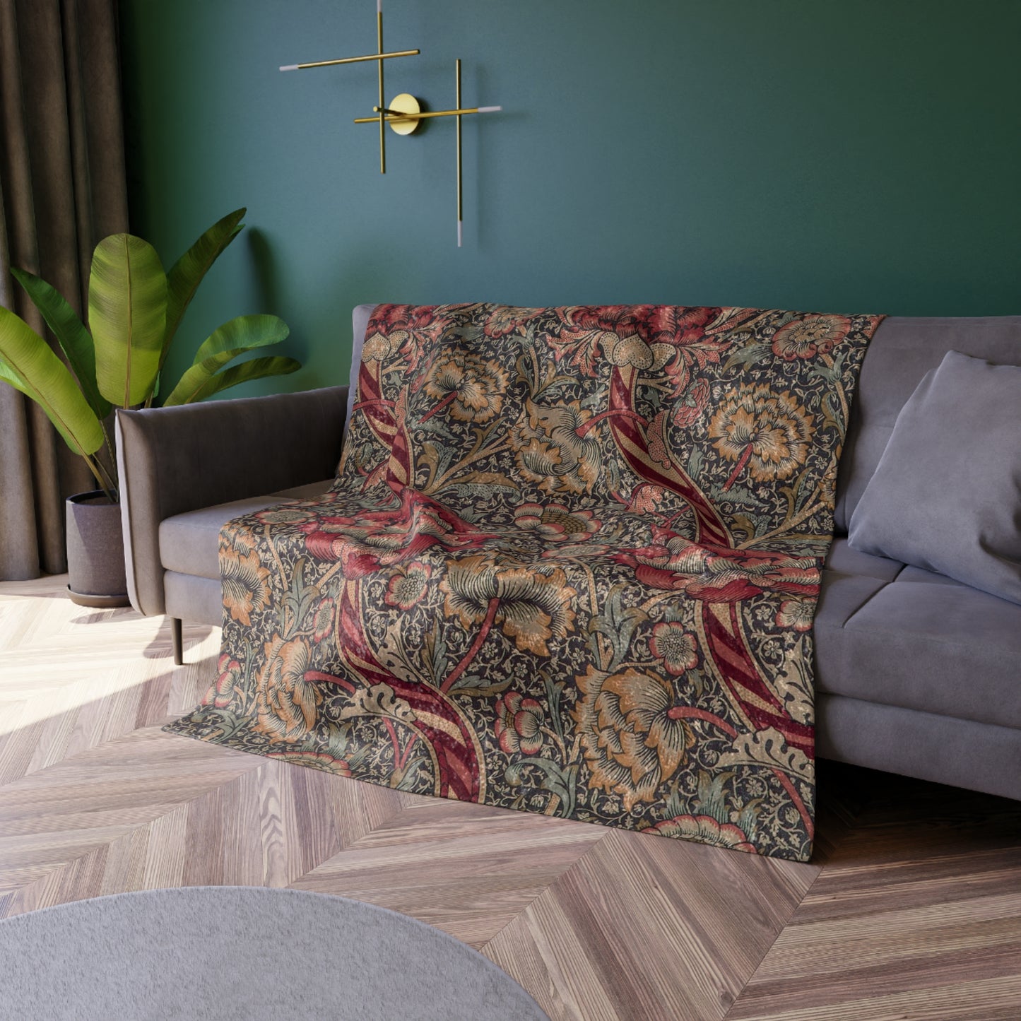 A crushed velvet blanket with a William Morris floral pattern in red and green colours, laid flat with hemmed edges visible.