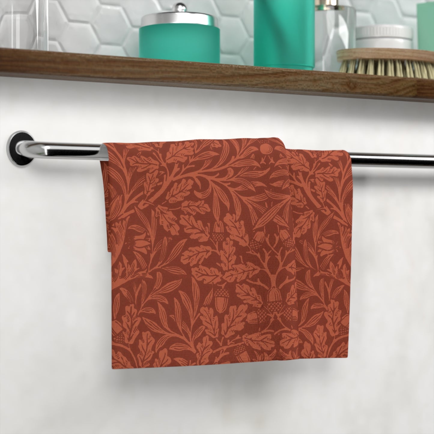 Red floral patterned towel hanging on a rack with a bathroom setting in the background.