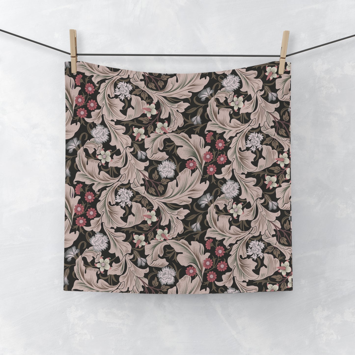 Floral patterned washcloth hanging on a line against a white background