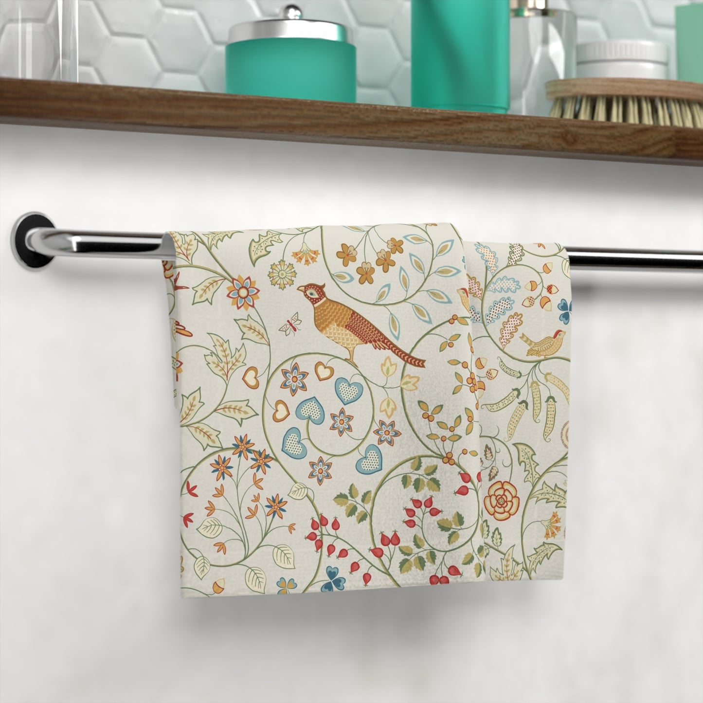 Decorative towel with floral and bird pattern hanging on a rack in a bathroom.