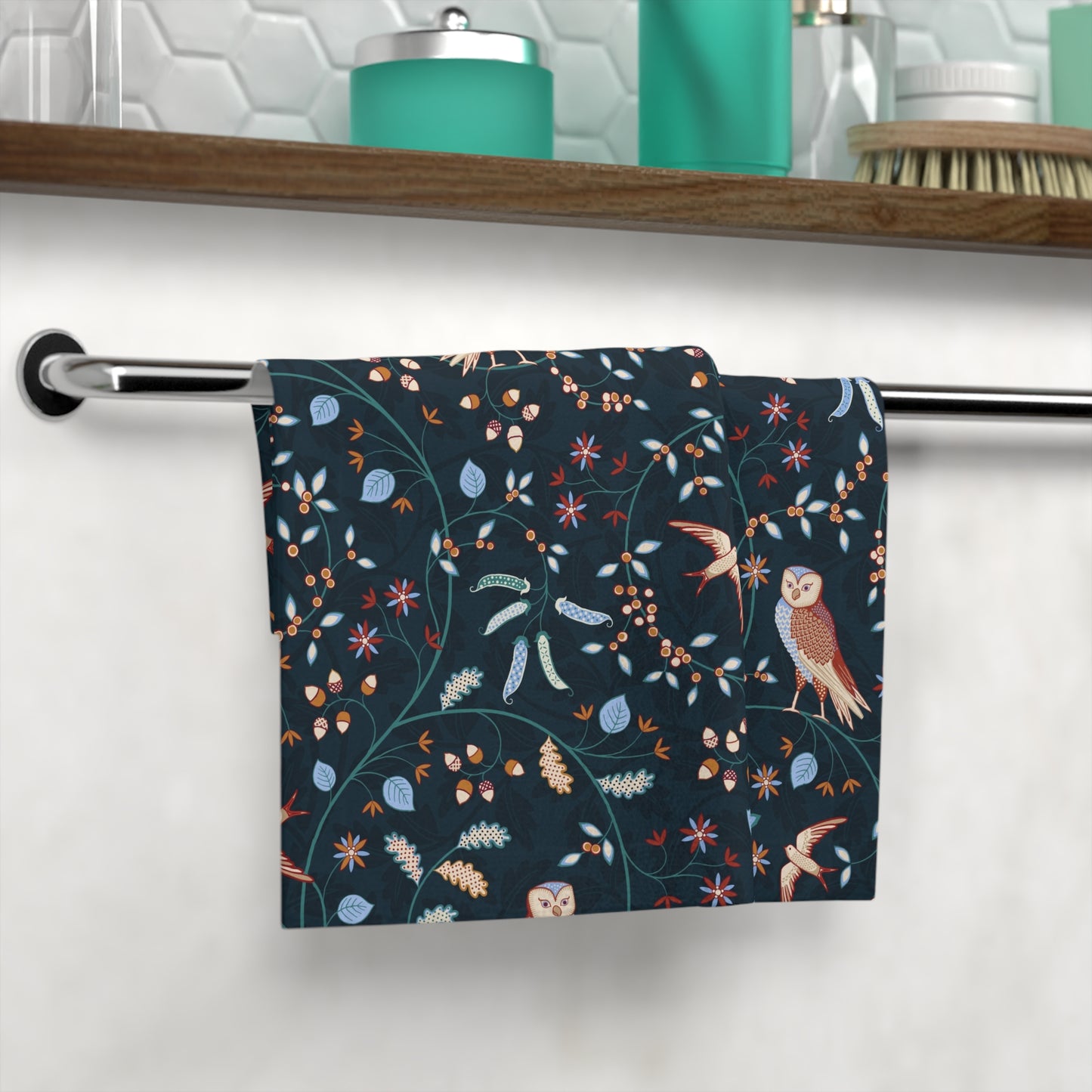 Decorative towel with owl and floral pattern hanging on a rack in a bathroom.