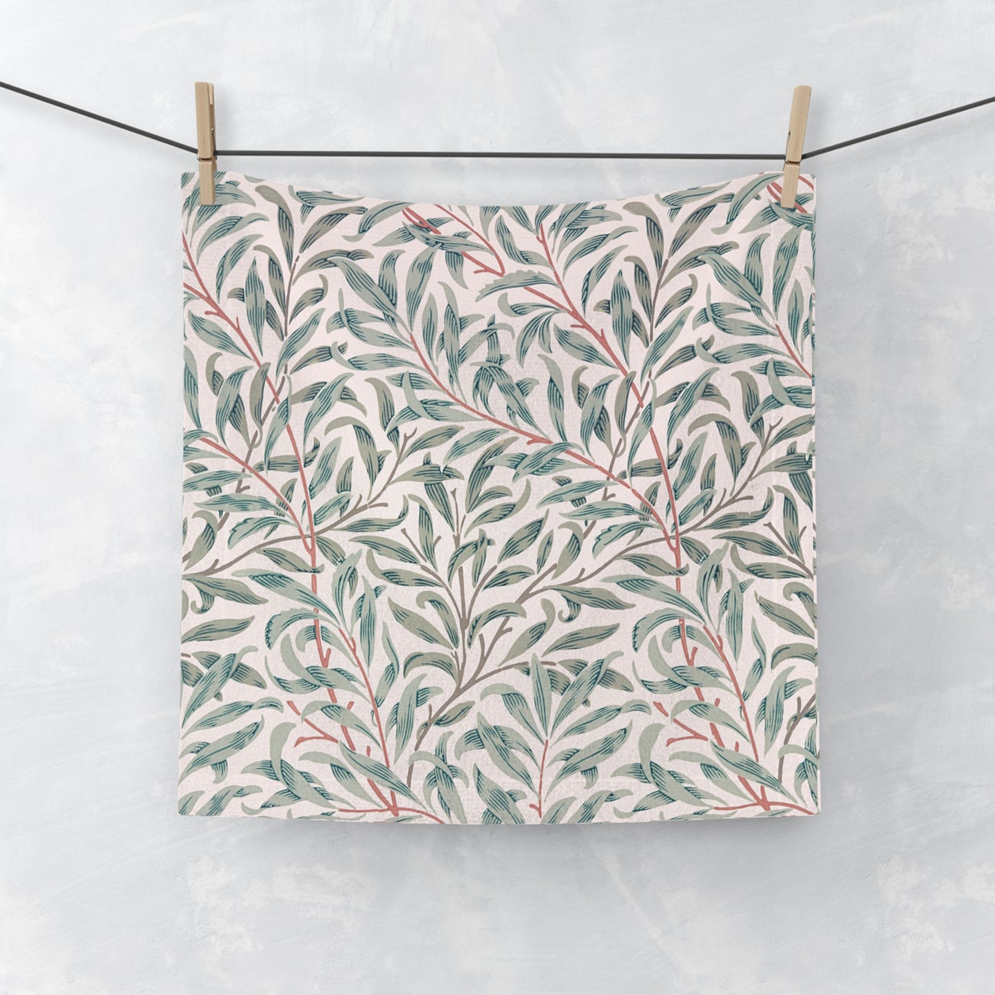Floral patterned washcloth hanging on a line against a light background
