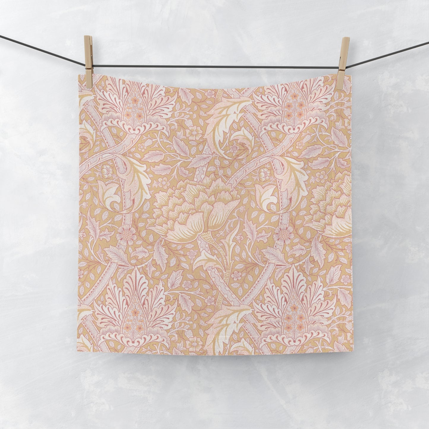 Floral patterned washcloth hanging on a wire with a white background