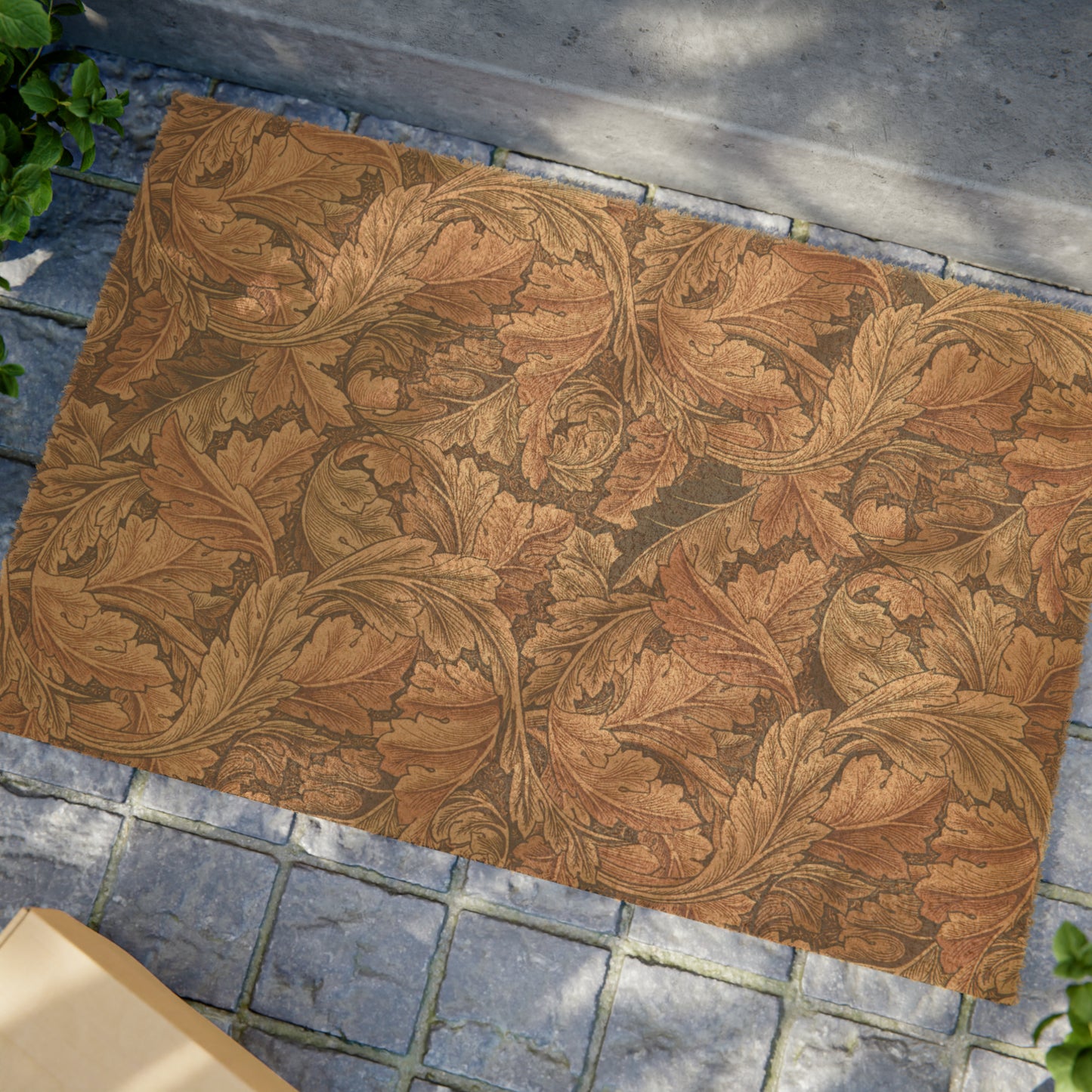 A rectangular coconut coir doormat with an intricate brown leaf William Morris & Co pattern and a solid black vinyl backing, designed for indoor and outdoor use.