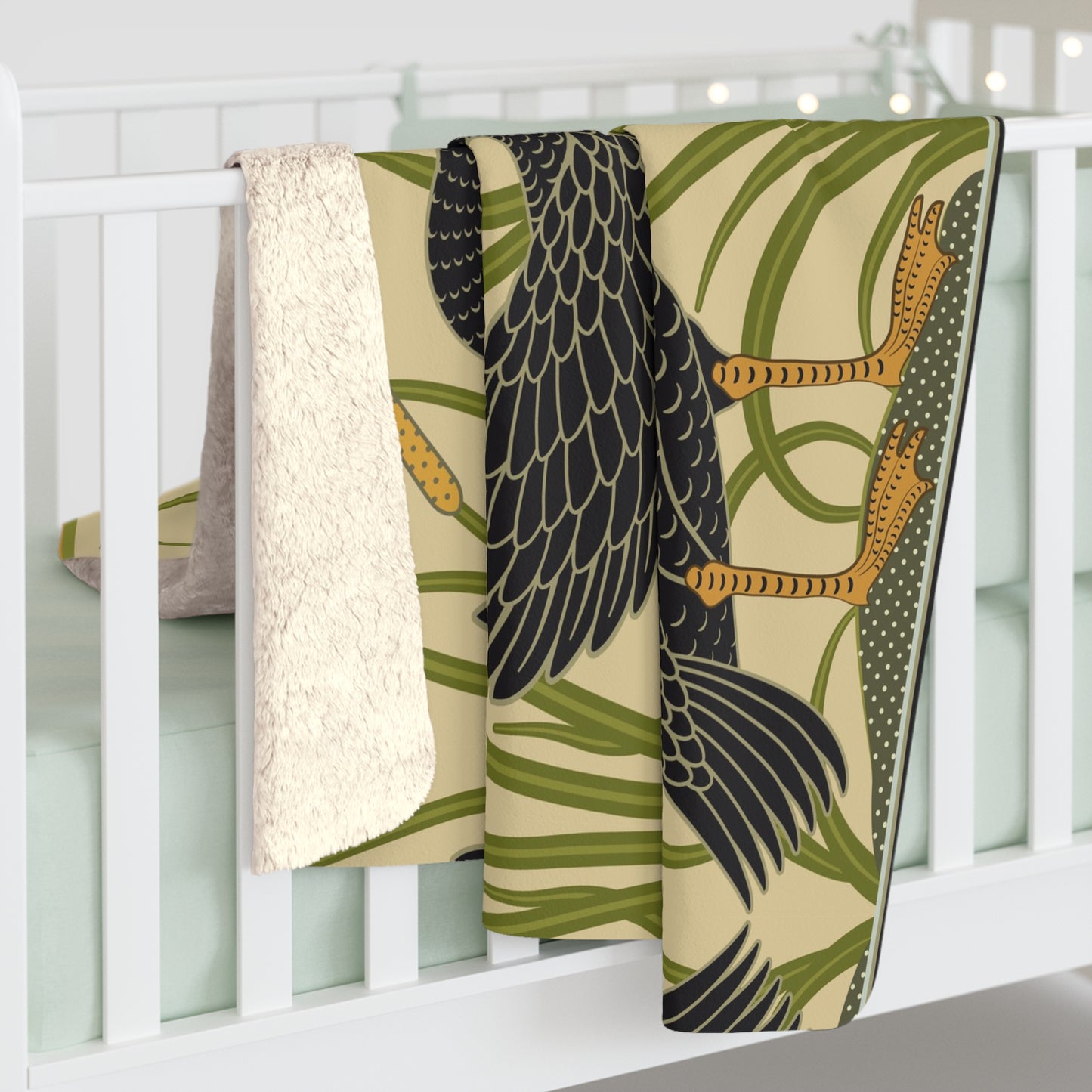 A Sherpa fleece blanket with a pattern inspired by William Morris, featuring black swans and green foliage on a beige background.