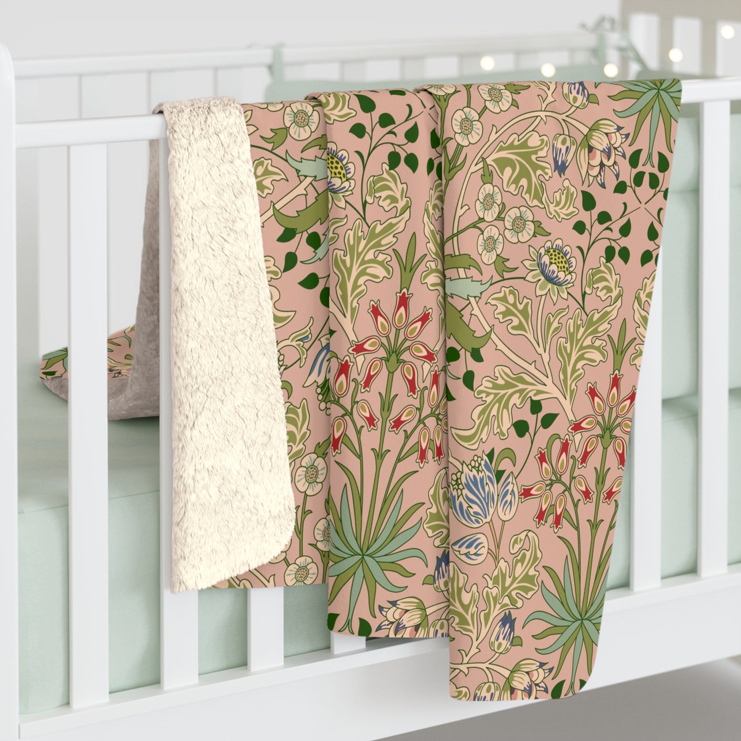 A Sherpa fleece blanket with a floral pattern in pink, green and beige colours on a pink background.