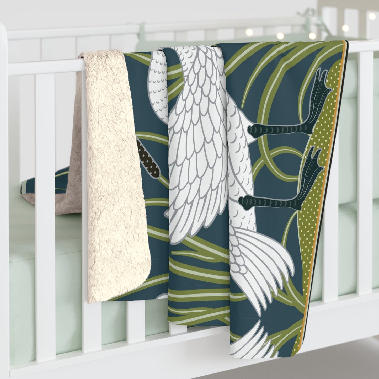 A Sherpa fleece blanket with a floral and swan William Morris & Co pattern in white and green colours on a dark background.