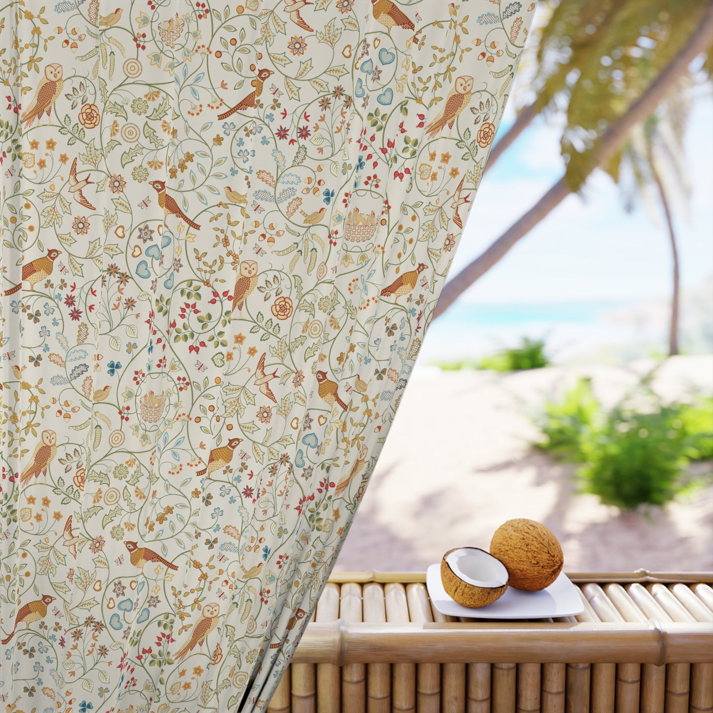 Decorative curtain with bird and floral pattern in front of a beach view.