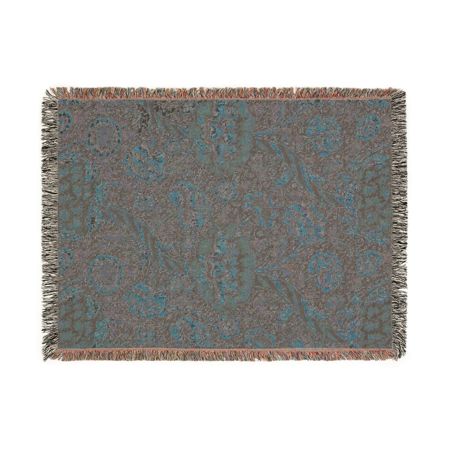 A woven cotton blanket with a geometric and floral William Morris & Co pattern in red, blue, beige, and brown colours, with fringed edges.