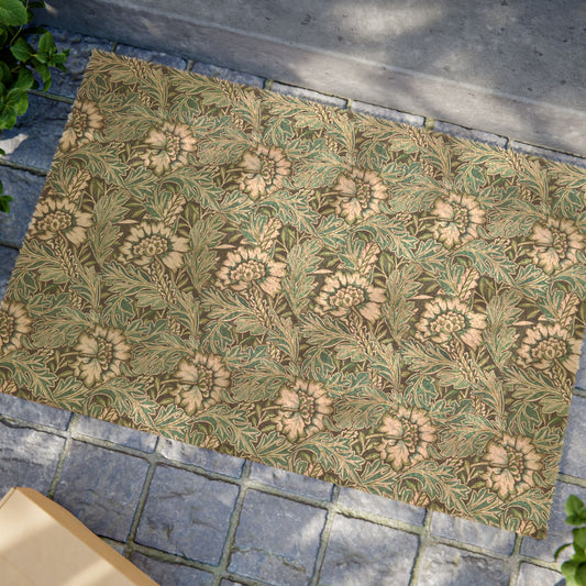 A rectangular area rug with a classic William Morris-style floral pattern in muted green, beige, and brown tones, laid out on a gray stone pavement.
