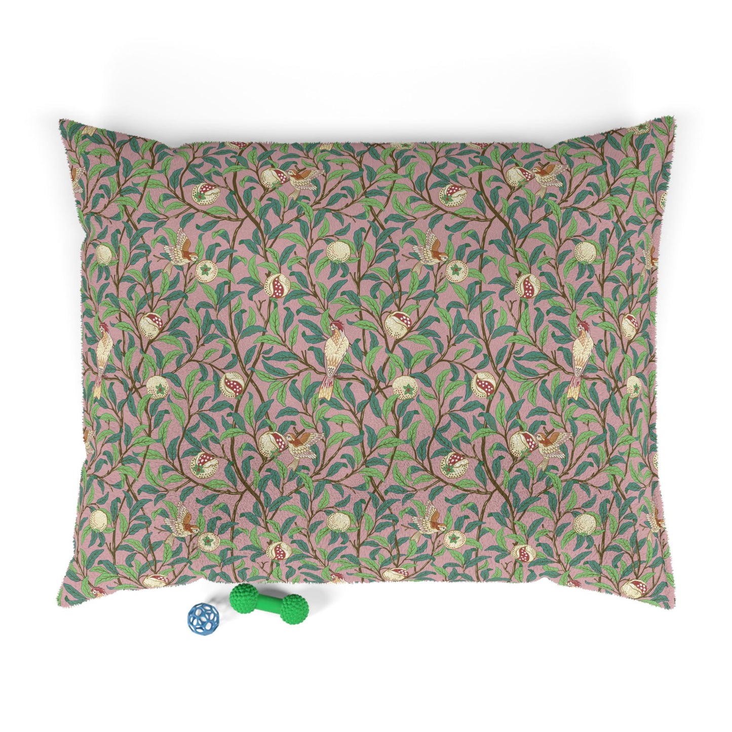 Decorative pillow with floral and bird pattern on a pink background, accompanied by two small toys.